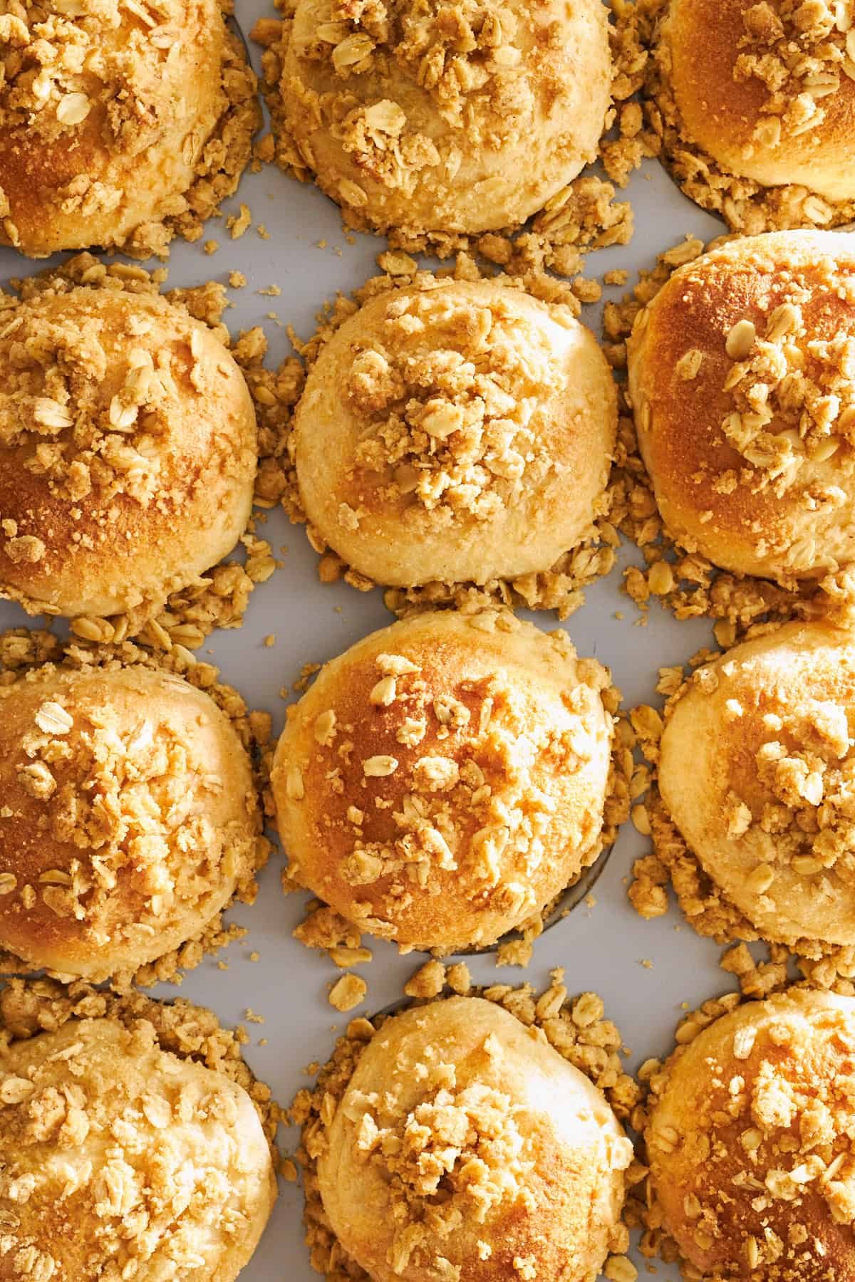 Baked dinner rolls topped with an oat crumble in a muffin tin.