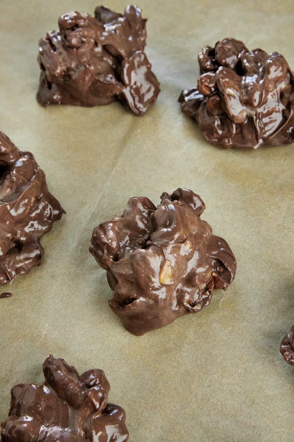 Hot caramel pecan clusters on a parchment lined baking sheet.