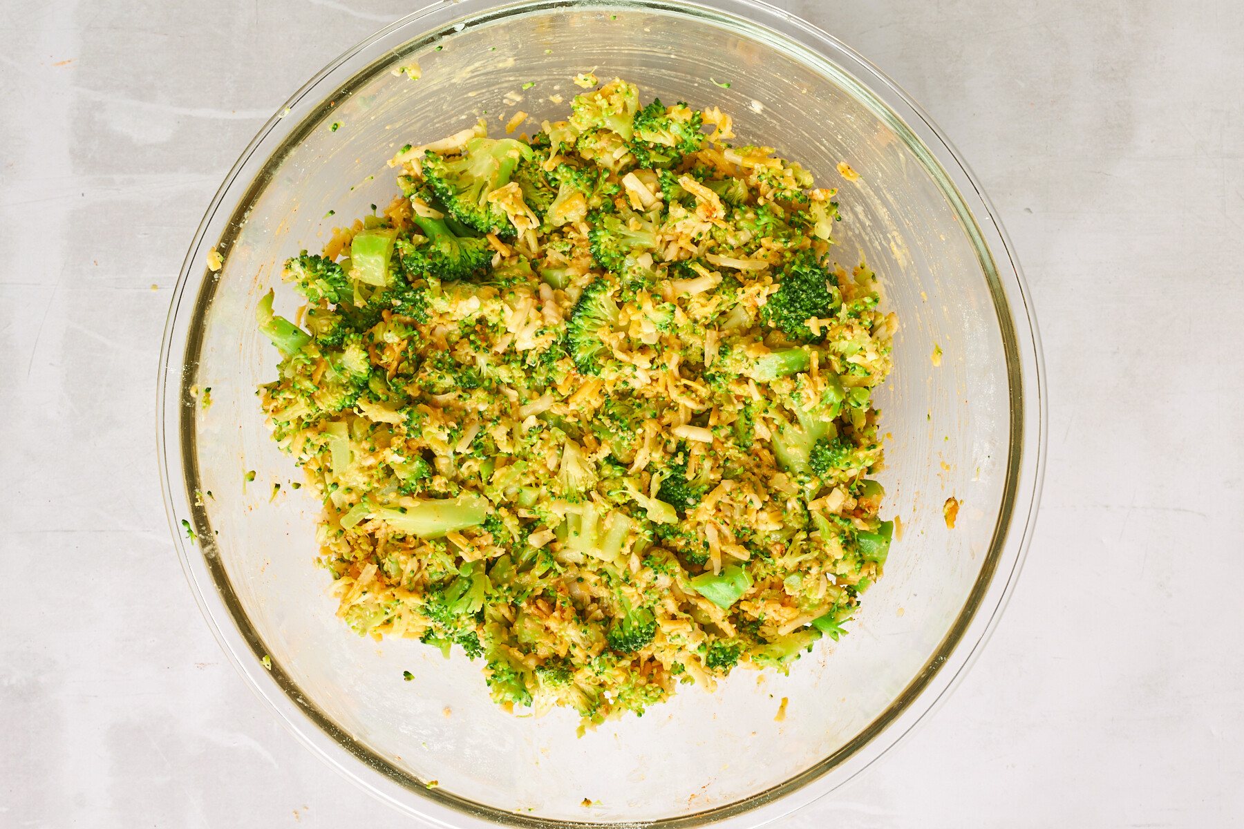 Cheesy broccoli fritters batter in a small bowl.
