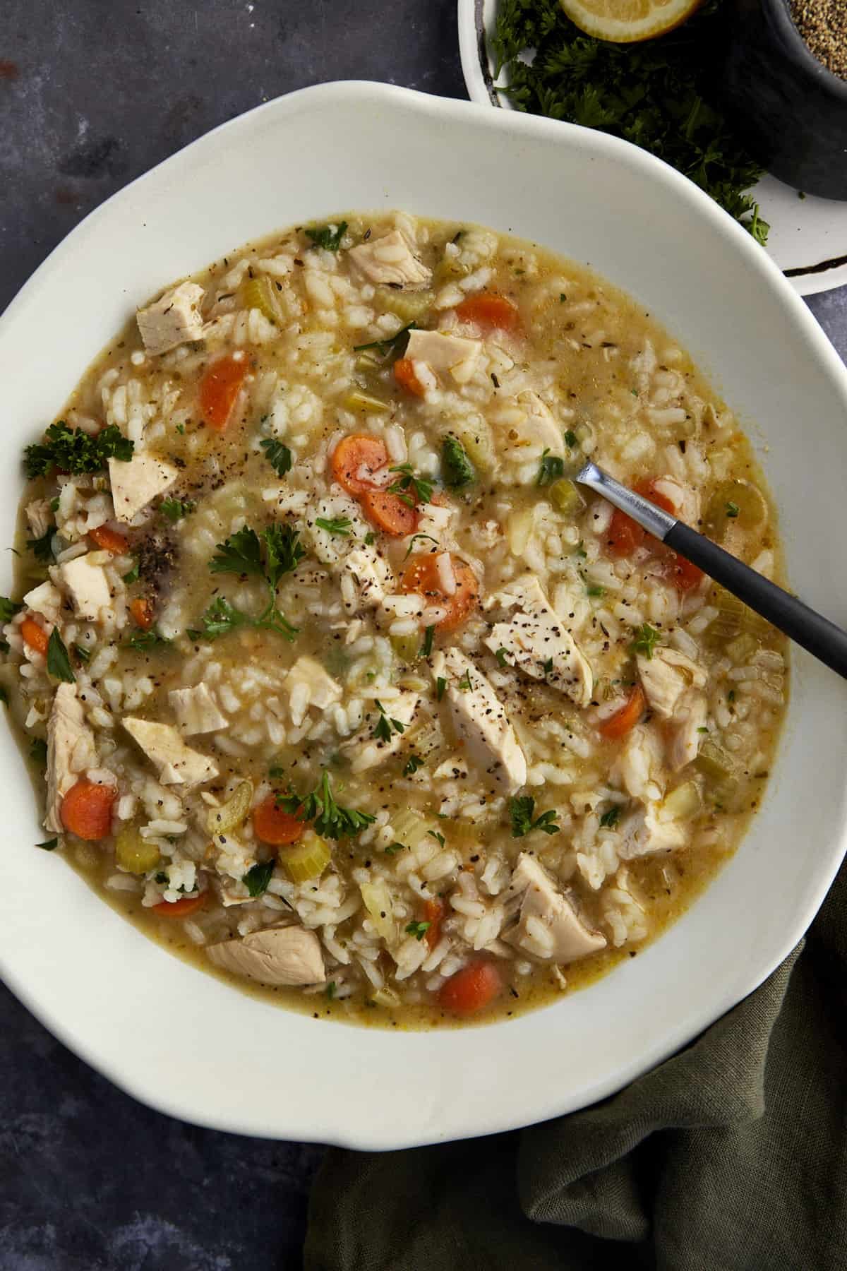 Overhead image of a bowl of chicken and rice soup with a spoon dipped in.
