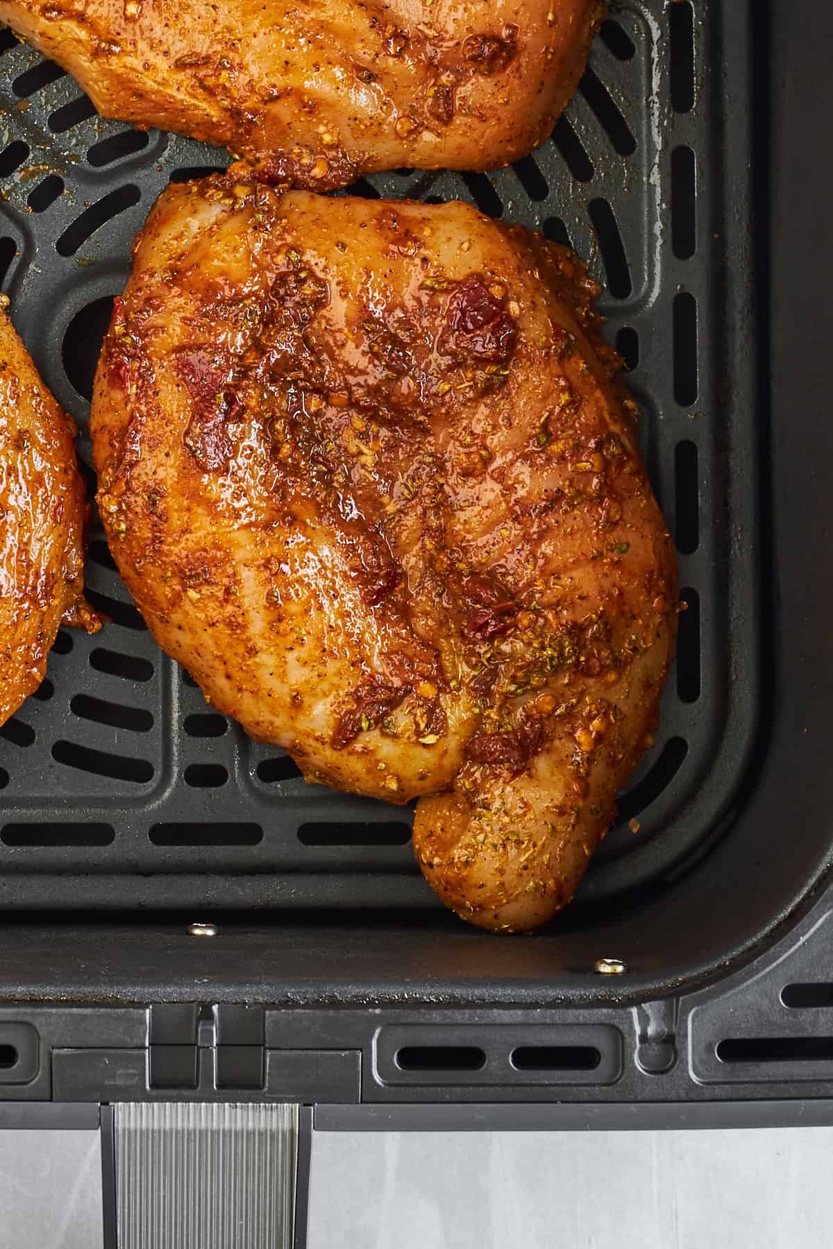 Raw chipotle chicken thighs in an air fryer.