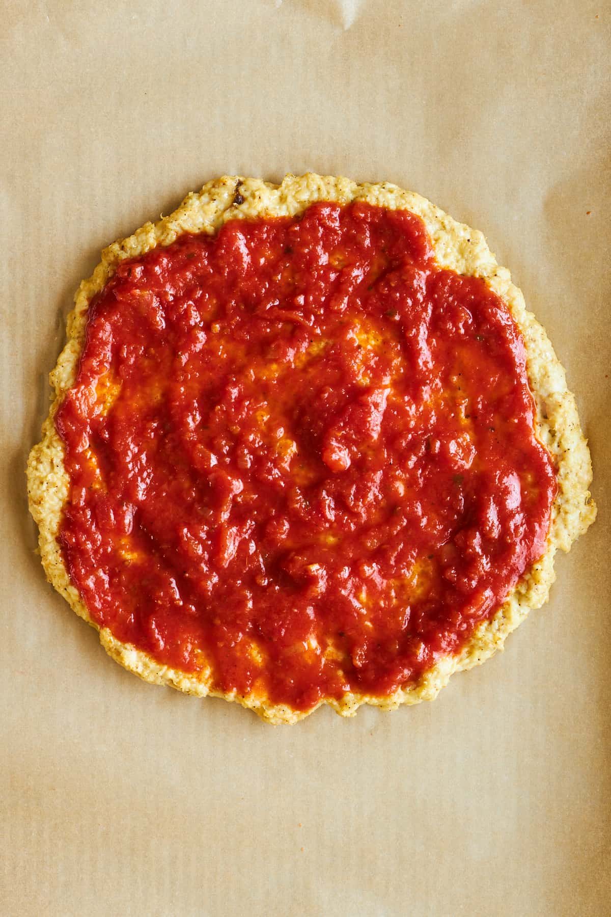Chicken pizza crust topped with marinara sauce.