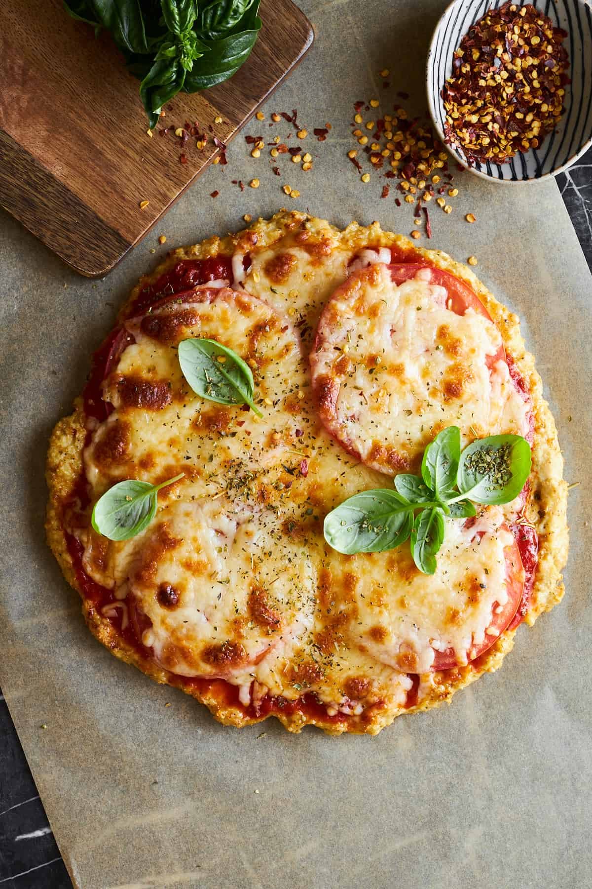 Chicken crust pizza topped with oregano and basil.