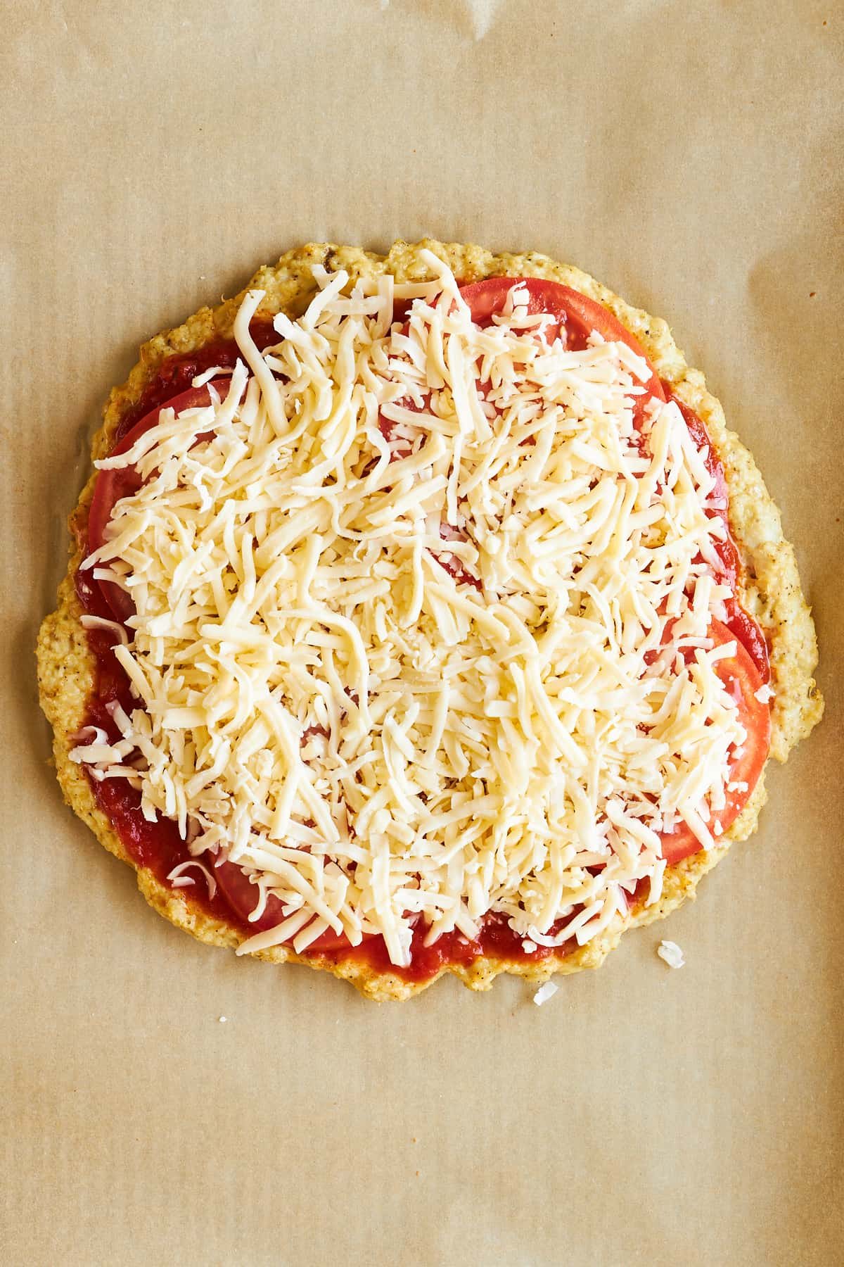 Chicken pizza crust topped with marinara sauce, tomatoes, and cheese.