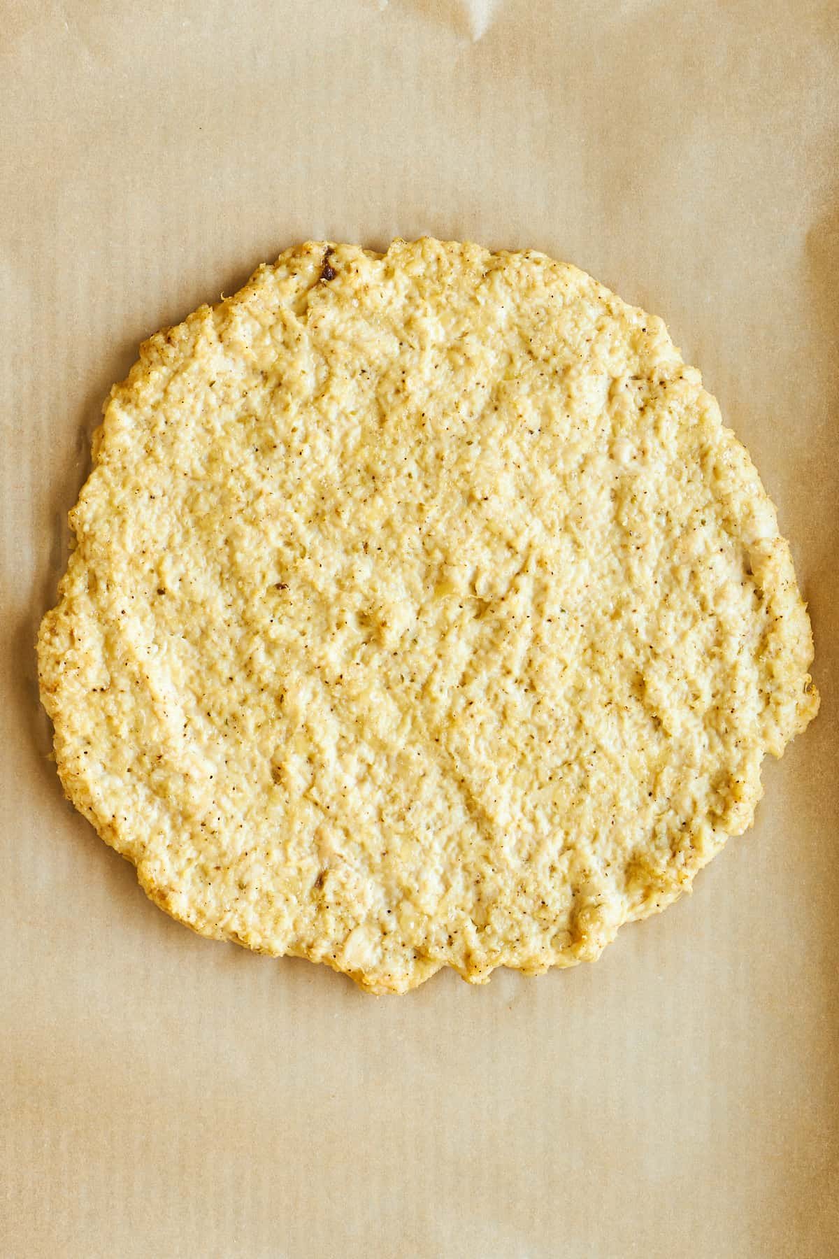 Baked chicken pizza crust on a baking sheet.