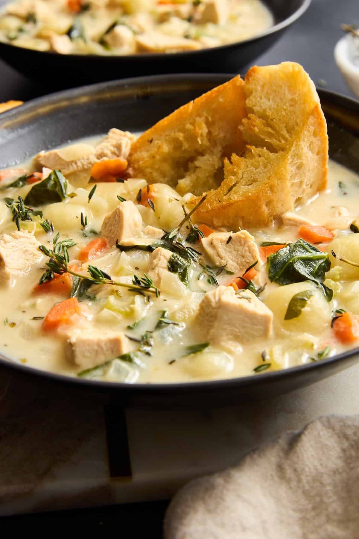 A bowl of Olive Garden chicken gnocchi soup topped with bread.