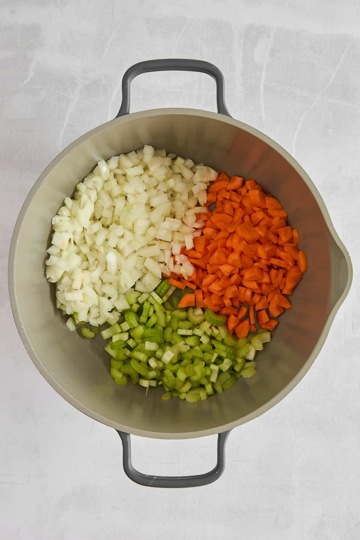 Onions, celery, and carrots in a pot.