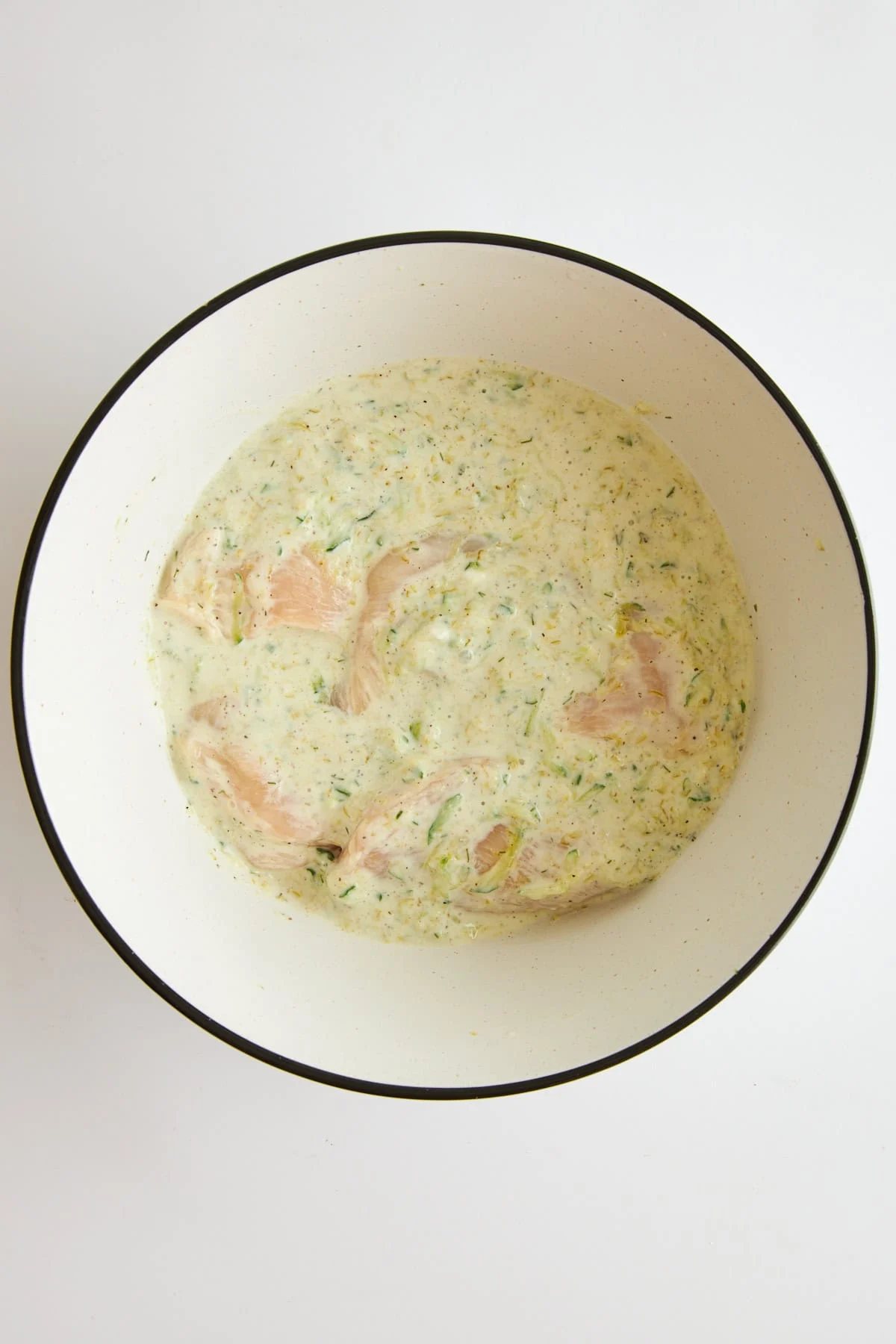 Raw chicken marinading in tzatziki chicken marinade.