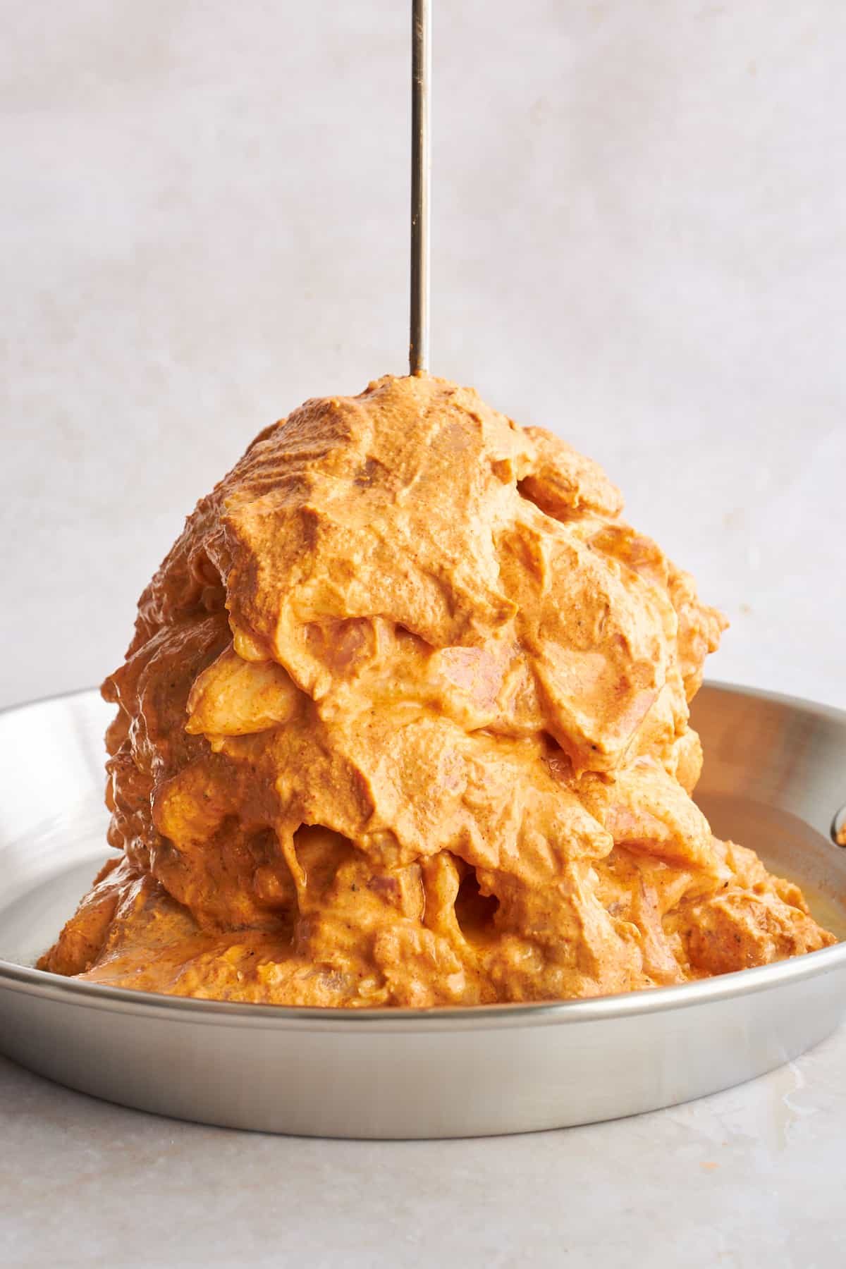 Raw chicken shawarma on a vertical skewer.