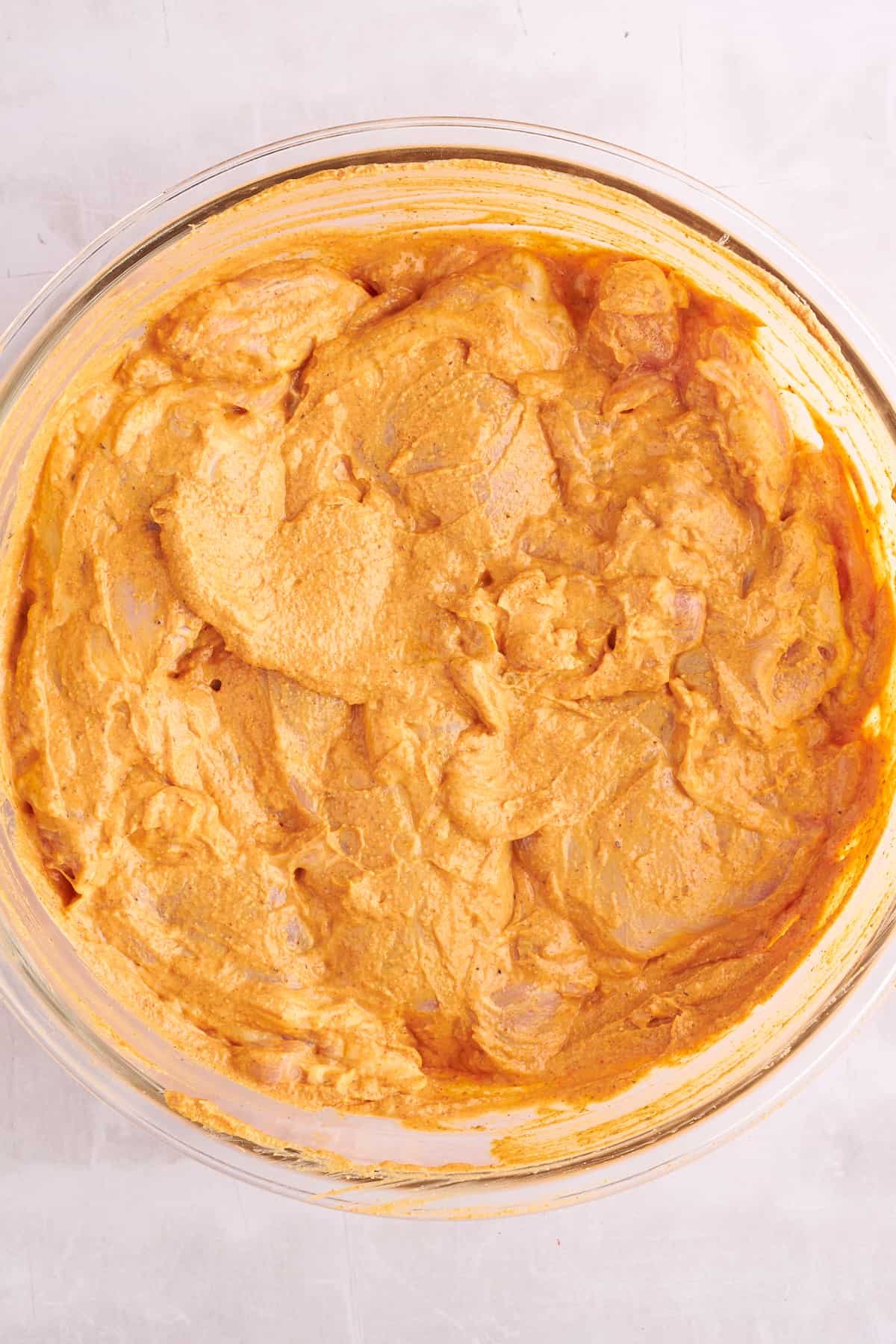 Raw chicken shawarma in a bowl coated in marinade.