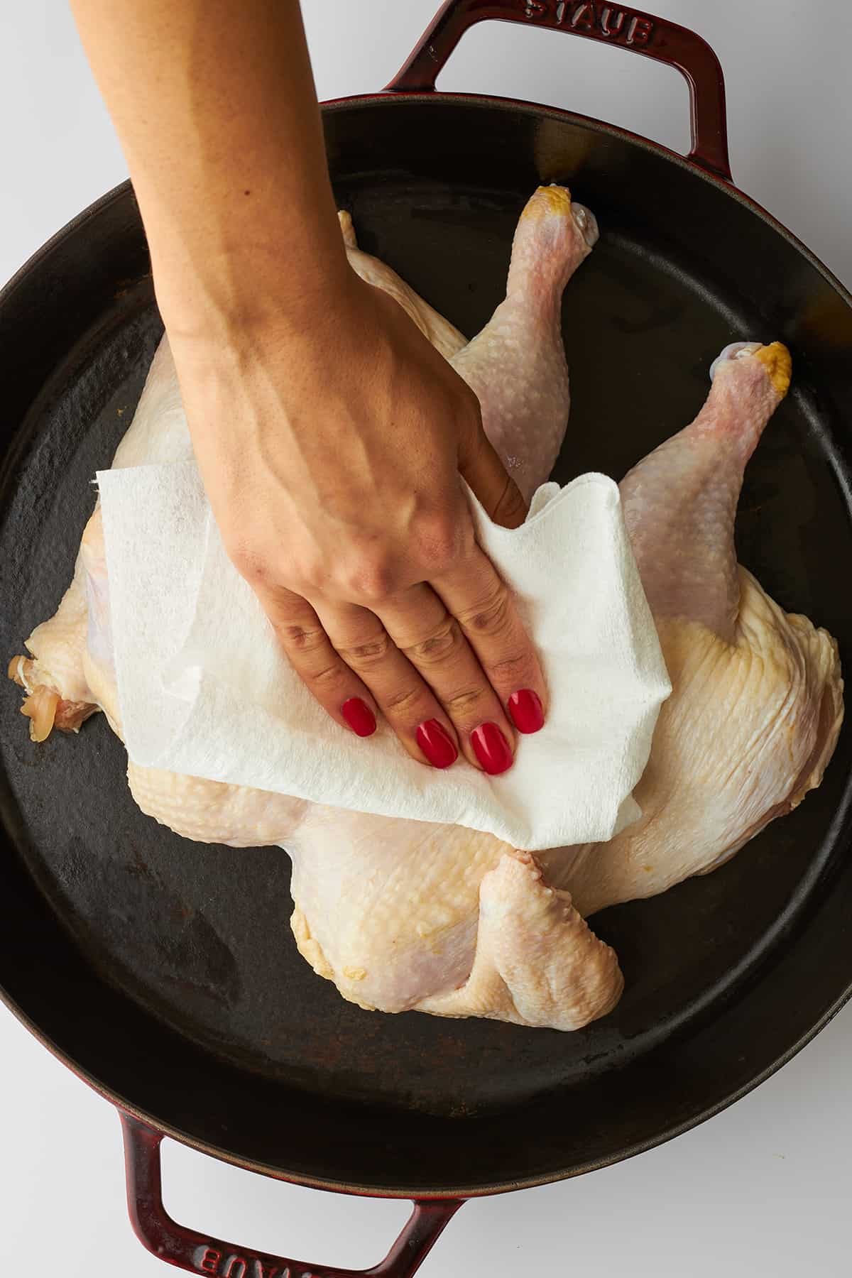 A hand drying chicken with a paper towel.