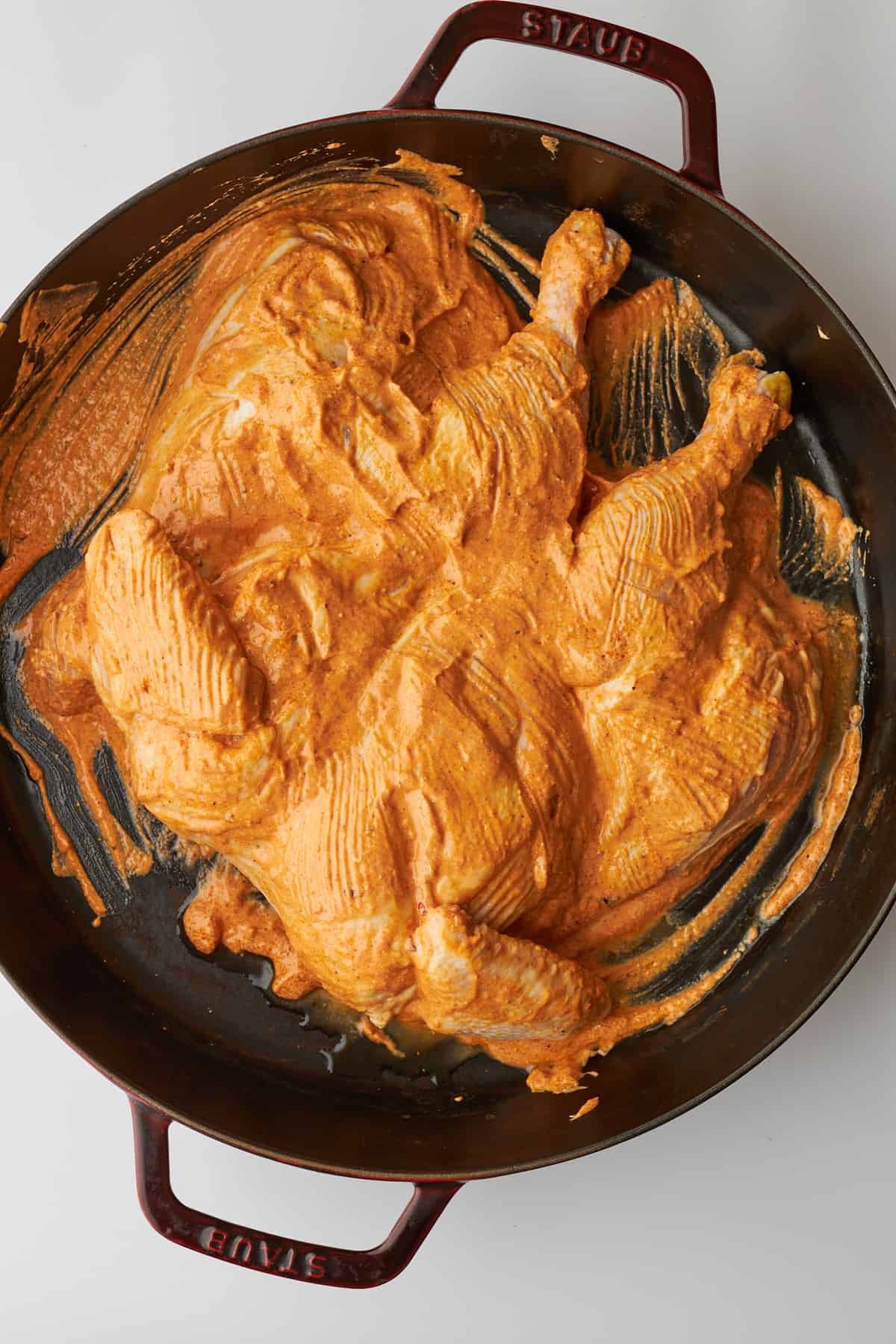 Marinated chicken tikka in a large cast iron skillet.