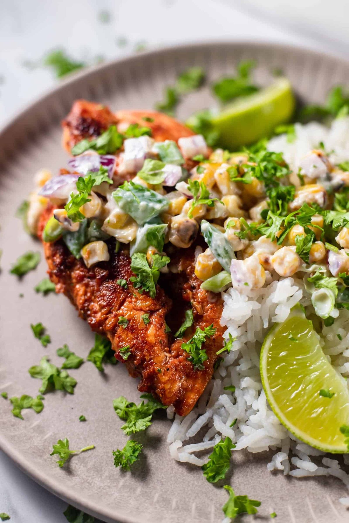 chipotle chicken topped with elote corn salad on top of rice topped with cilantro