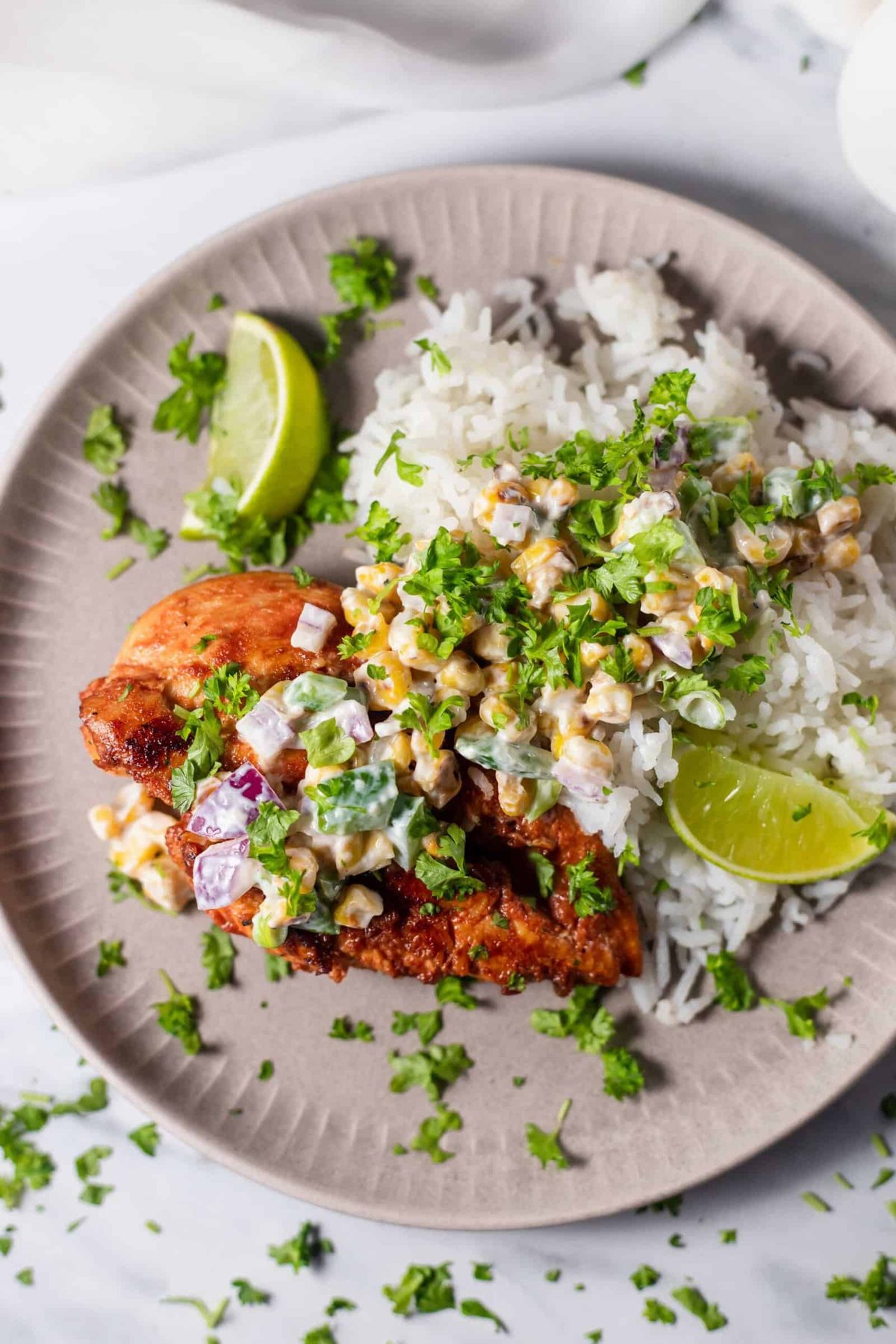 a plate of chipotle chicken with elote corn salad over a bed of rice