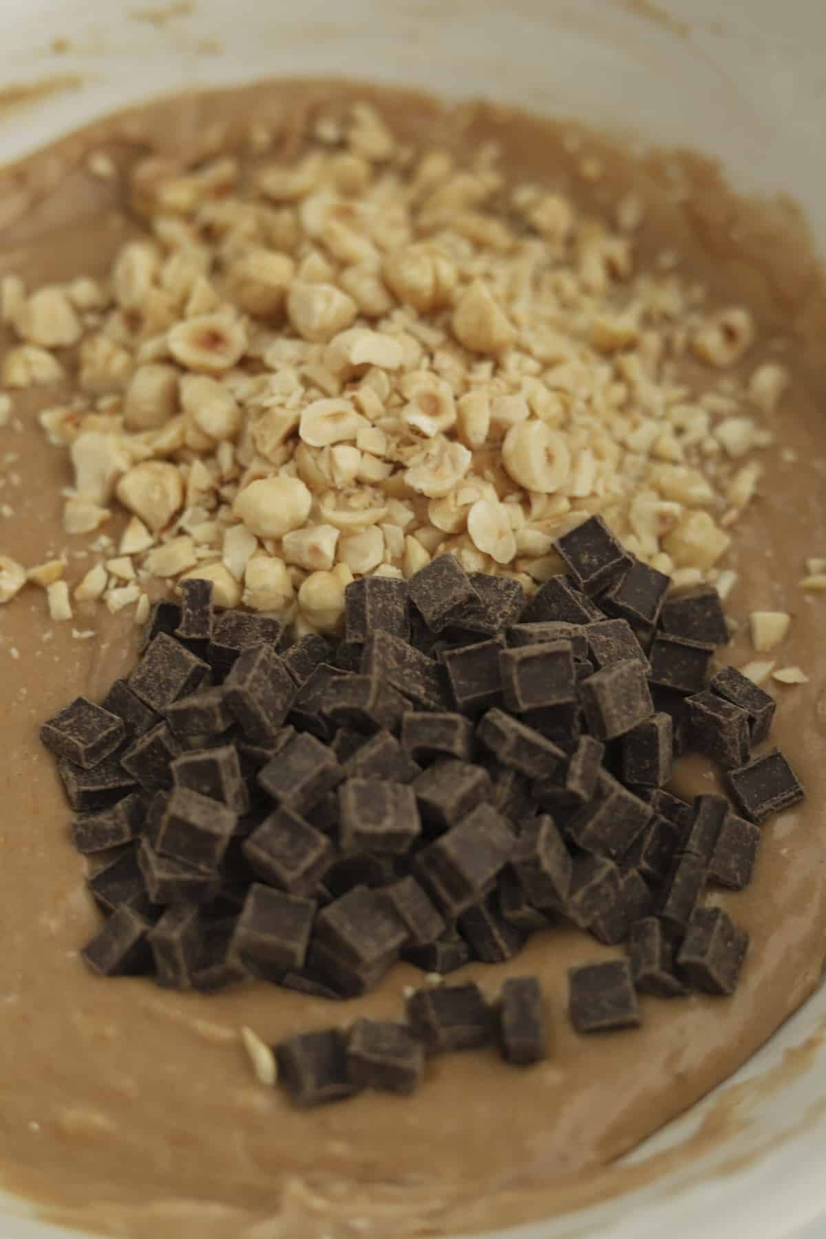 chocolate hazelnut banana bread batter with chocolate chunks and chopped hazelnuts on top