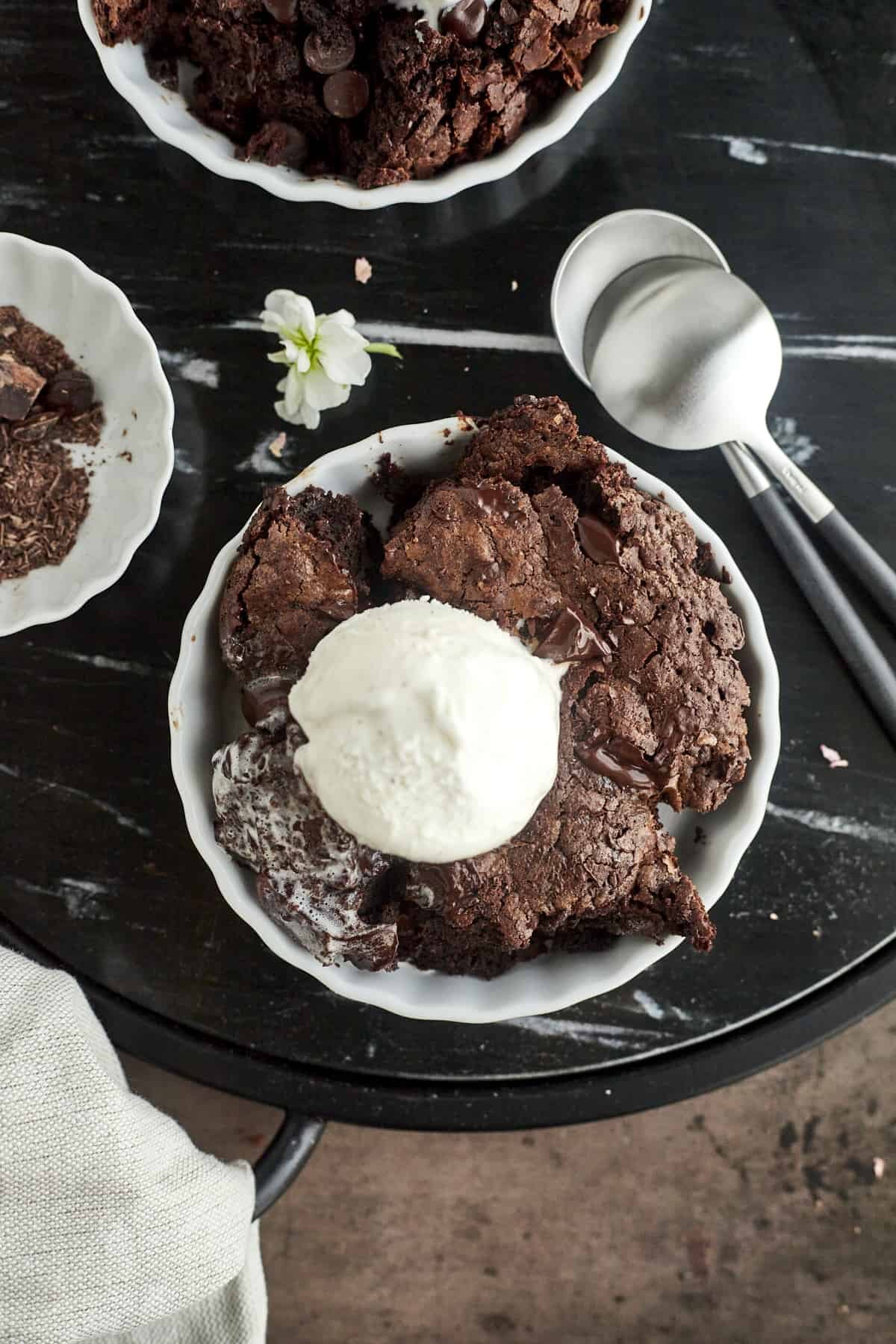 overhead image of small white bowls with servings of a brownie topped with vanilla ice cream with spoons on the side