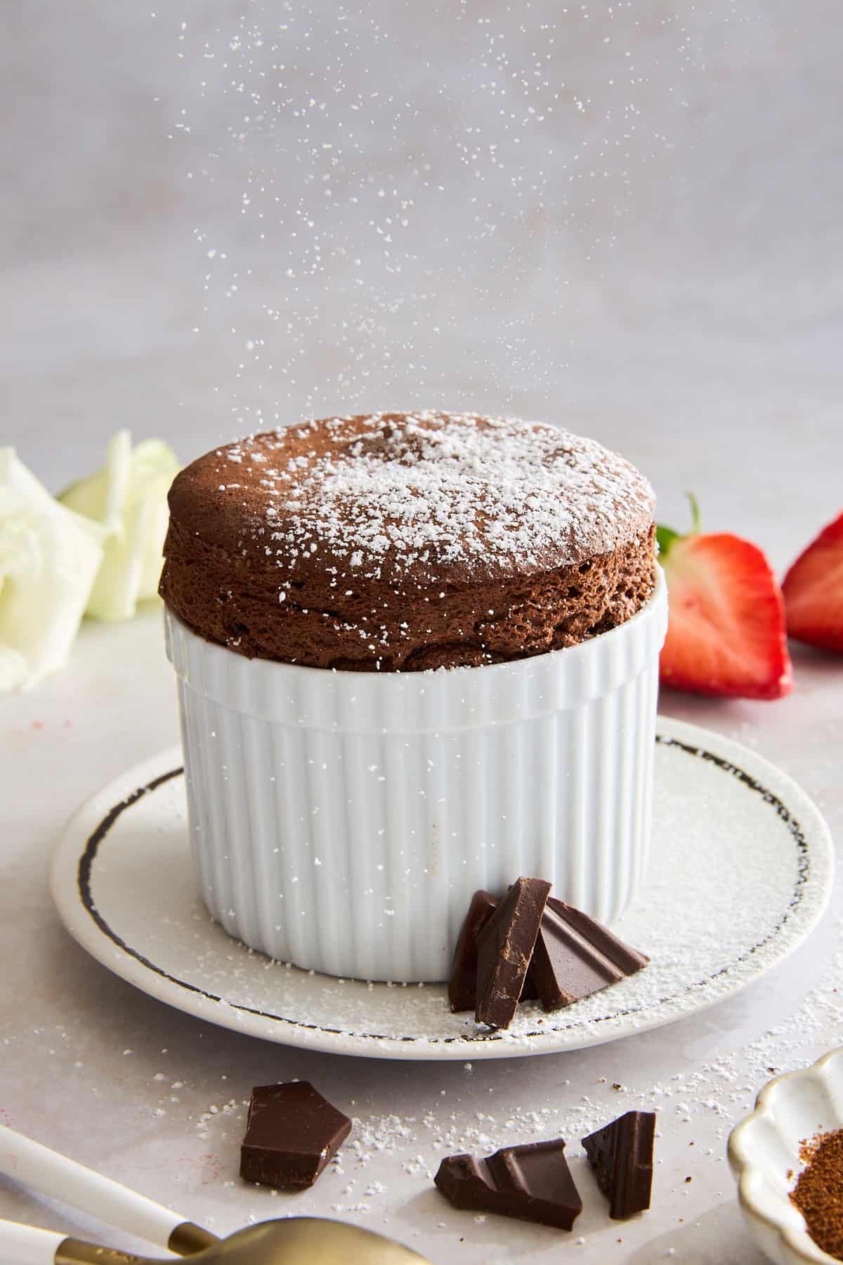 A ramekin of chocolate souffle topped with powdered sugar.