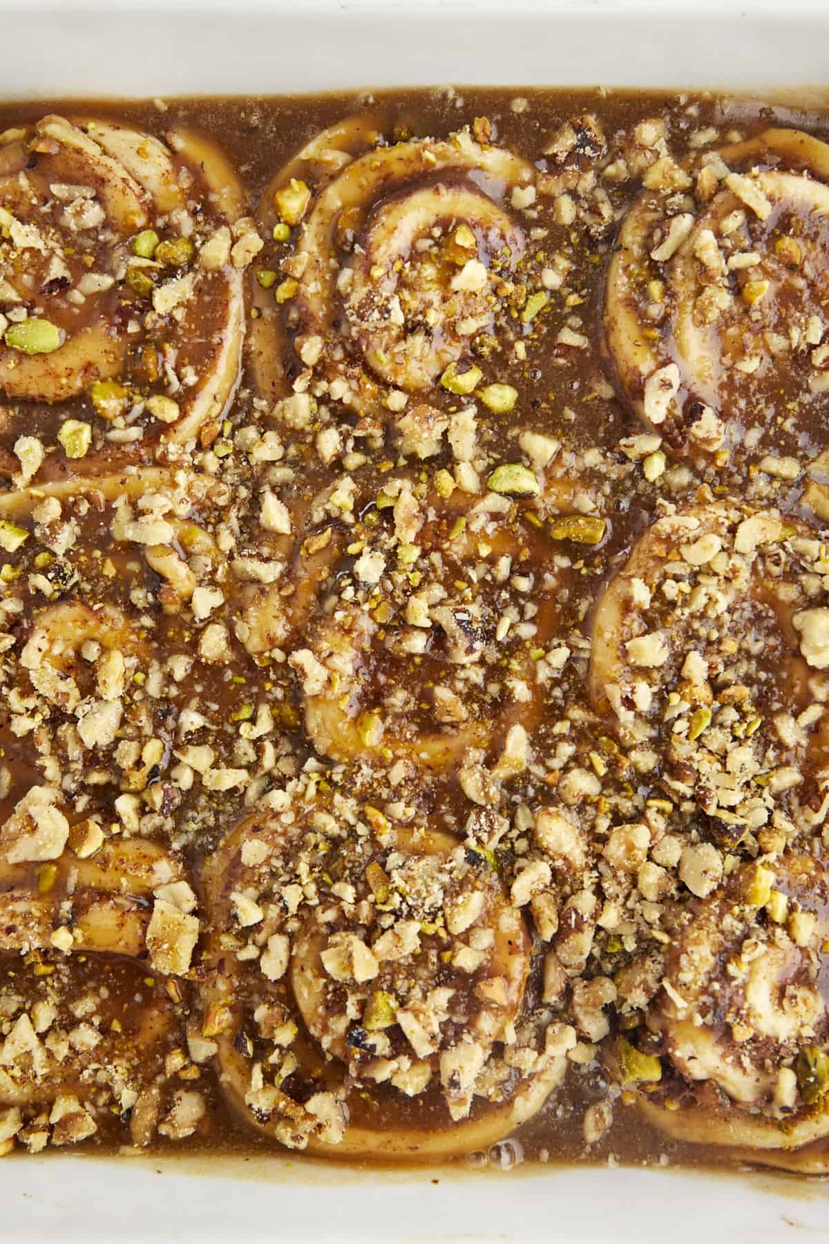 Cinnamon rolls with nuts in a baking dish topped with syrup