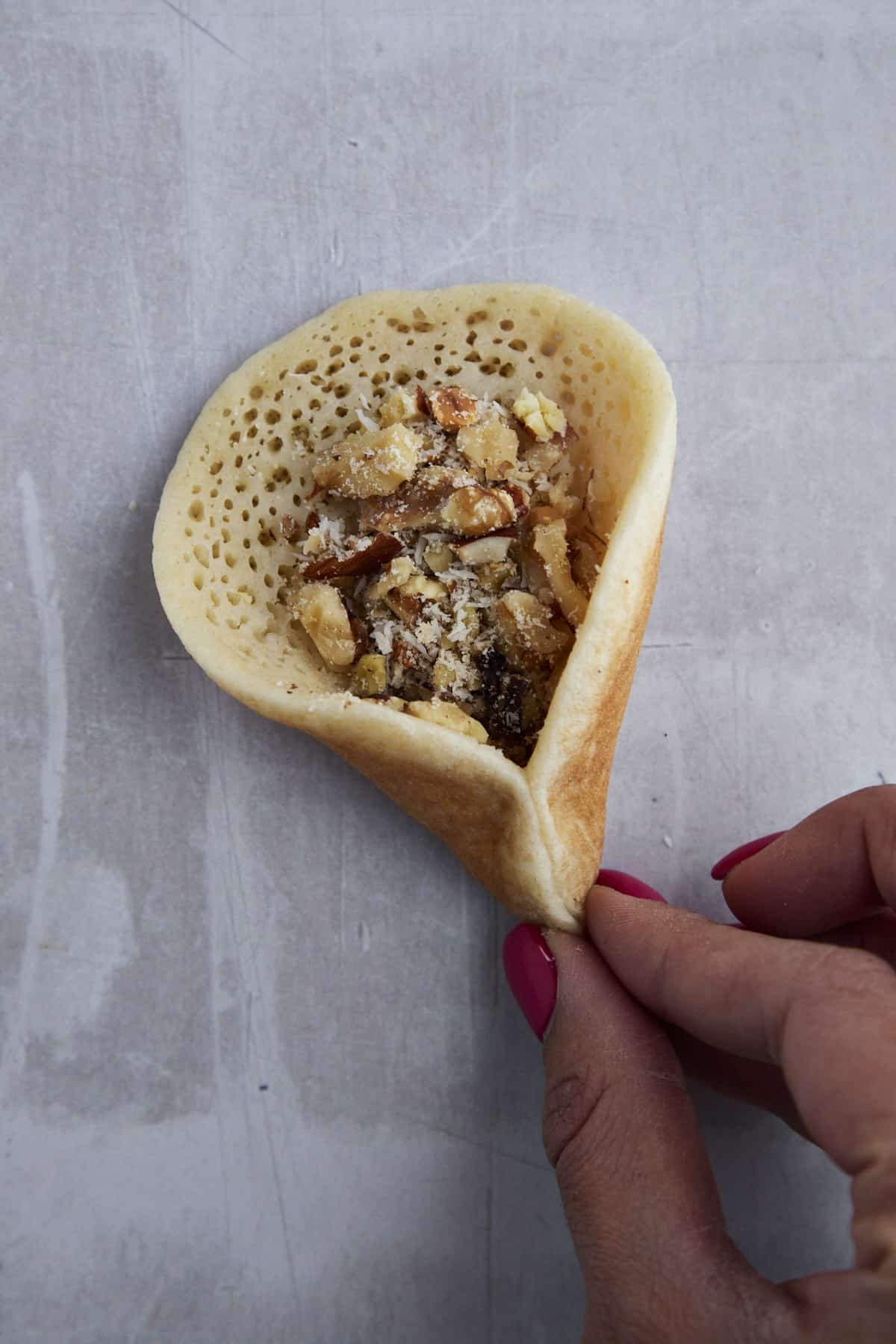 two fingers pinching qatayef dough together