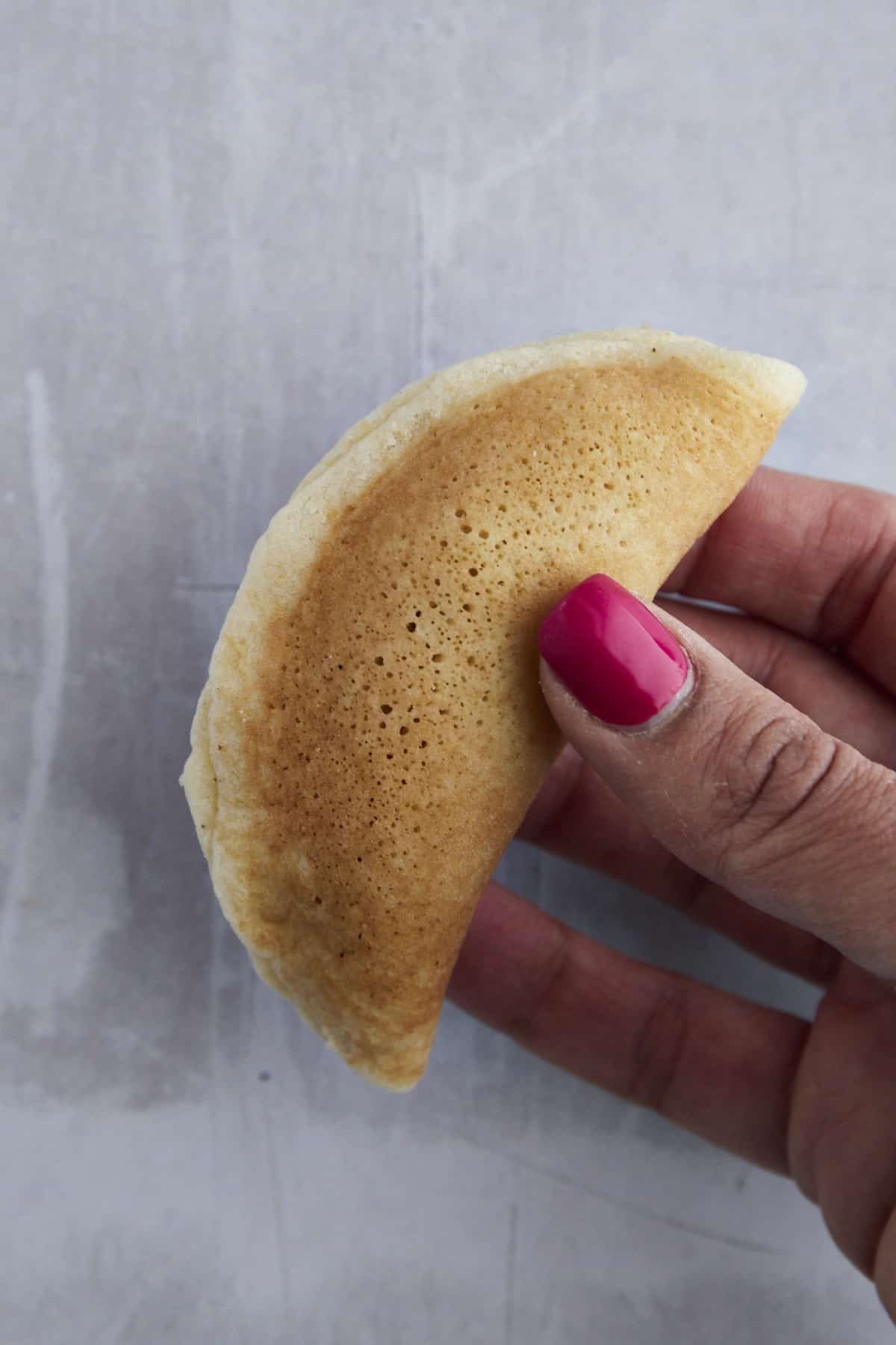 a hand holding a raw piece of atayef