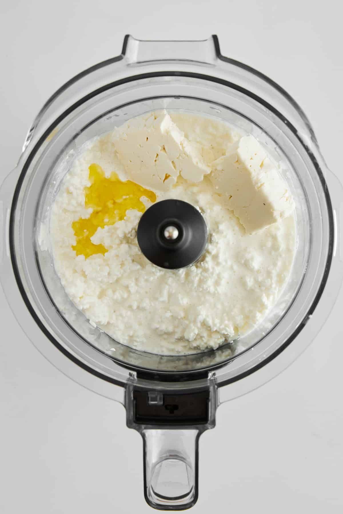 Cottage cheese, feta, and olive oil in a food processor.
