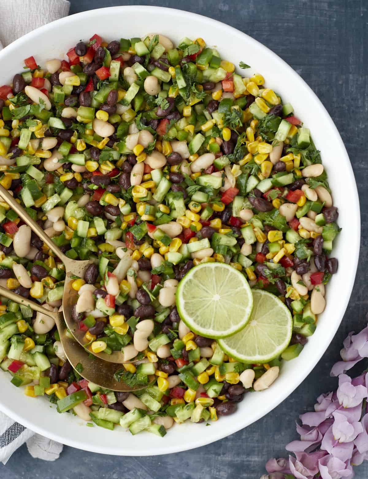 large white bowl with cowboy caviar, limes, and gold spring spoons