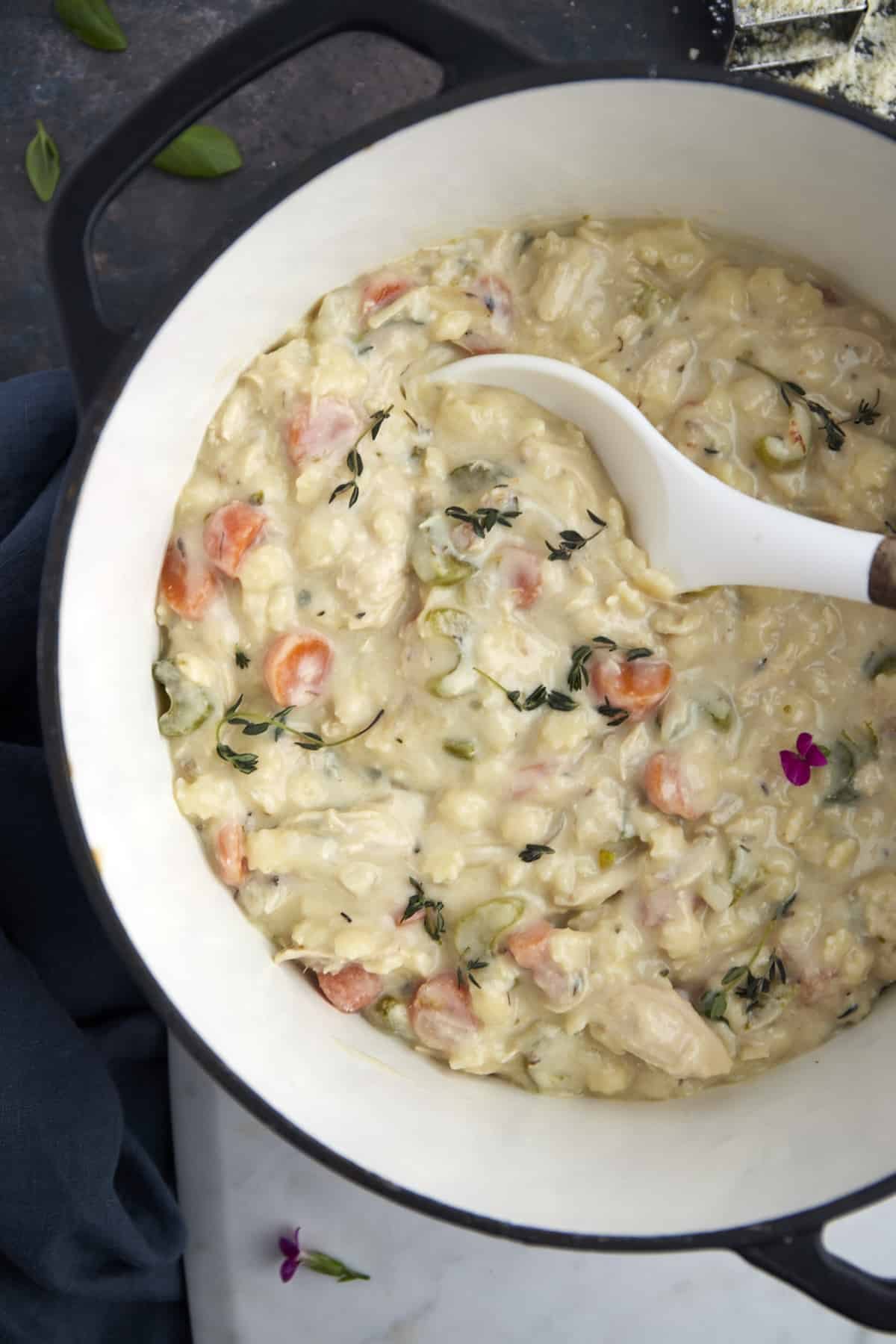 a bowl of silky chicken noodle soup being scooped with a spoon.