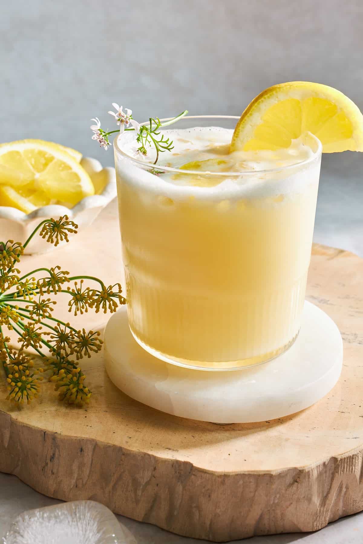 A glass of silky lemonade with a lemon wedge on the side.