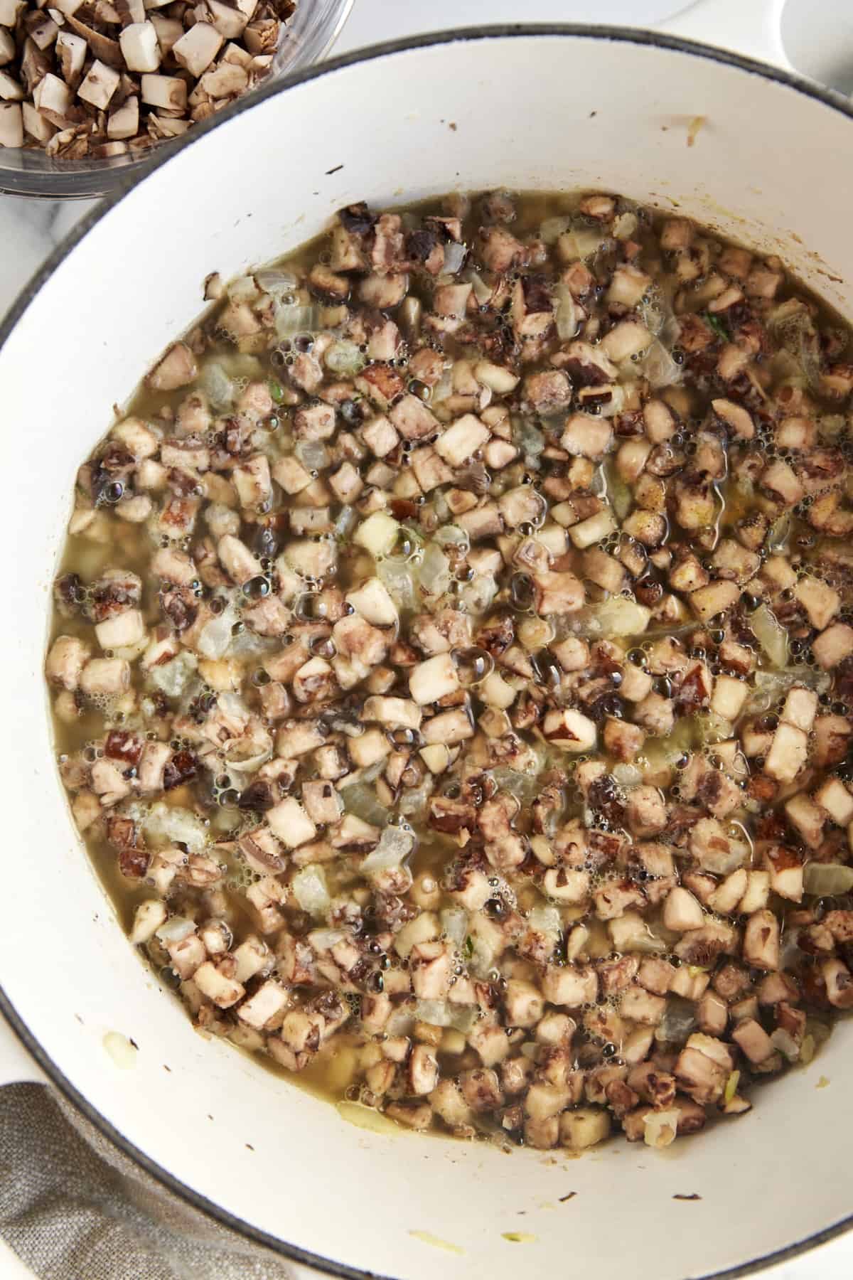 Onions, garlic, and mushrooms sautéing in butter and oil in a large pot.
