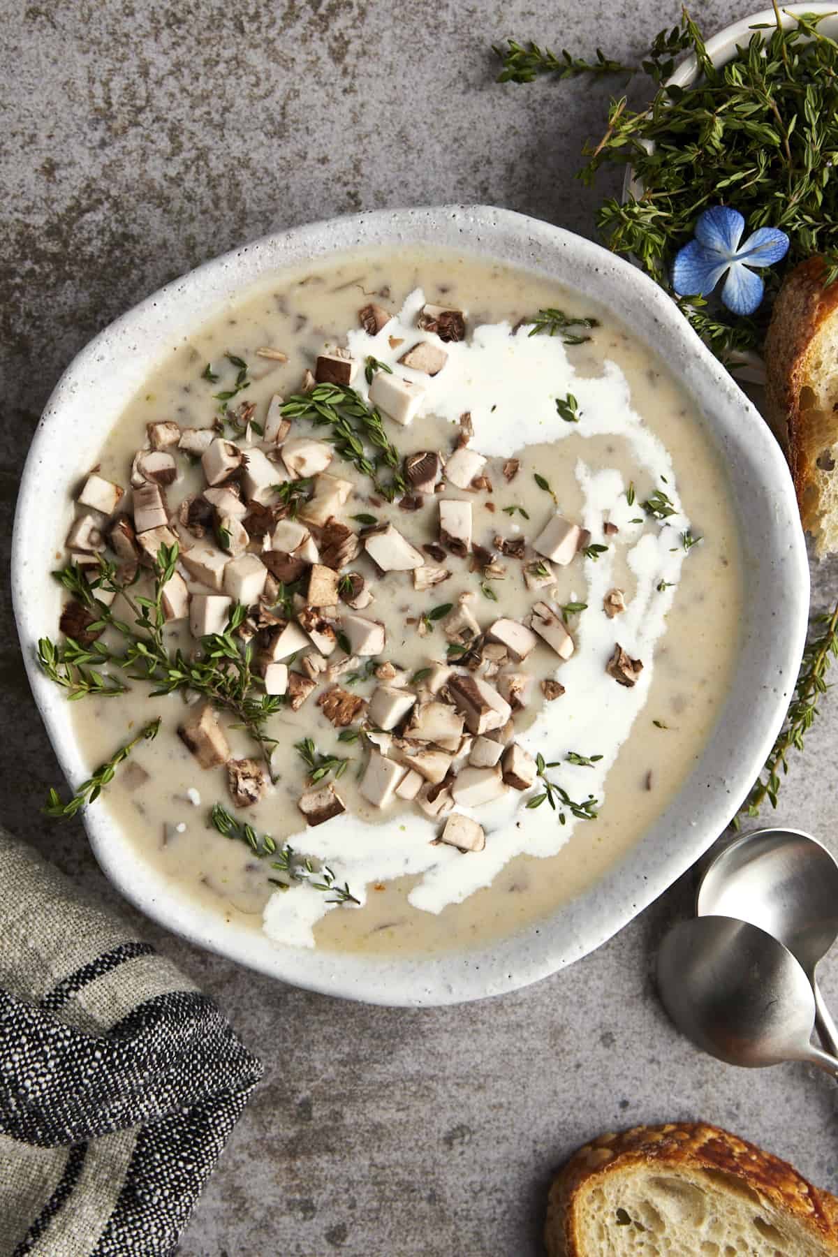 A bowl of silky mushroom soup topped with mushrooms and thyme.