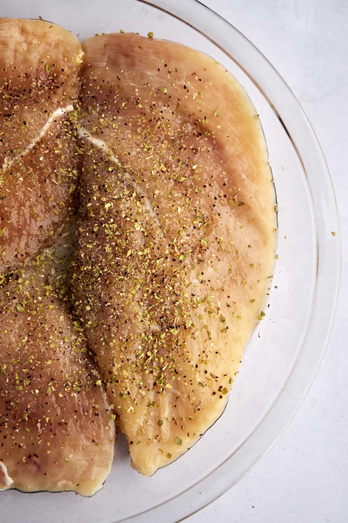 raw seasoned chicken breasts in a glass bowl