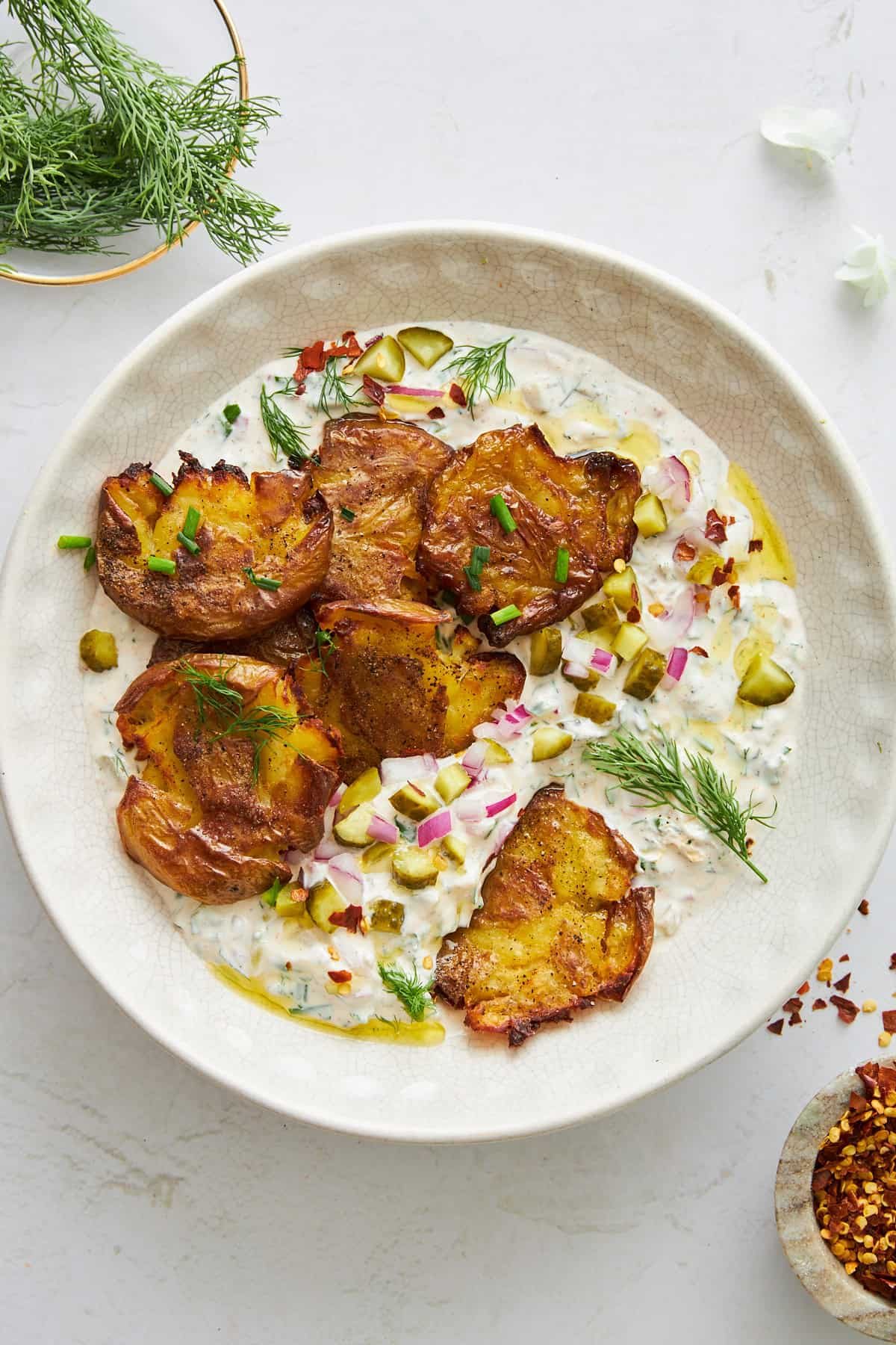 A bowl of labne topped with crackly potatoes.