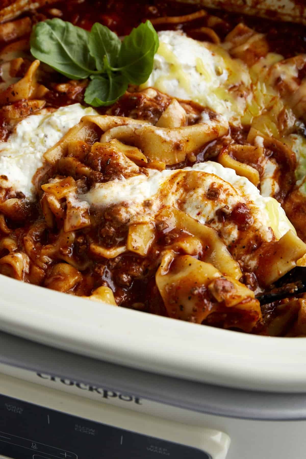 Close up of crockpot lasagna soup topped with cheese and fresh basil.