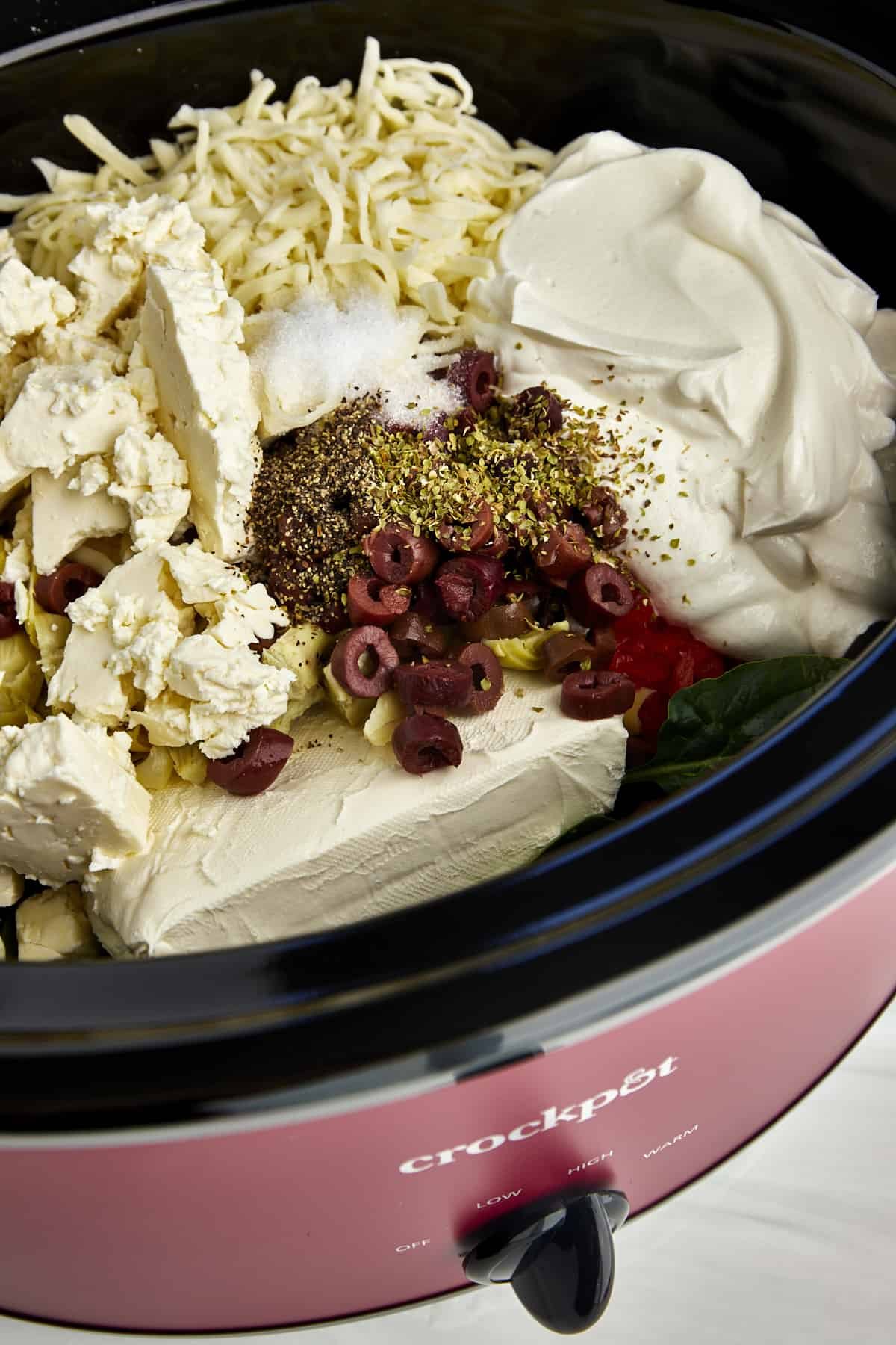 Ingredients for a warm spinach and artichoke dip recipe in a crockpot.