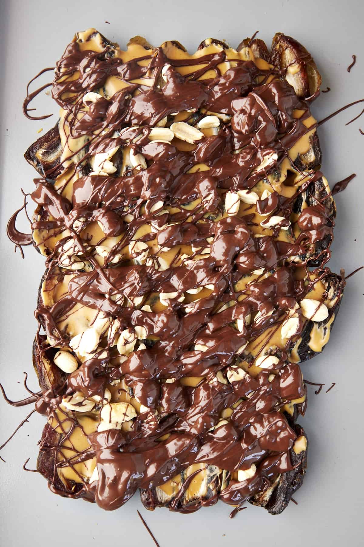 Dates topped with peanut butter, peanuts, and melted chocolate.