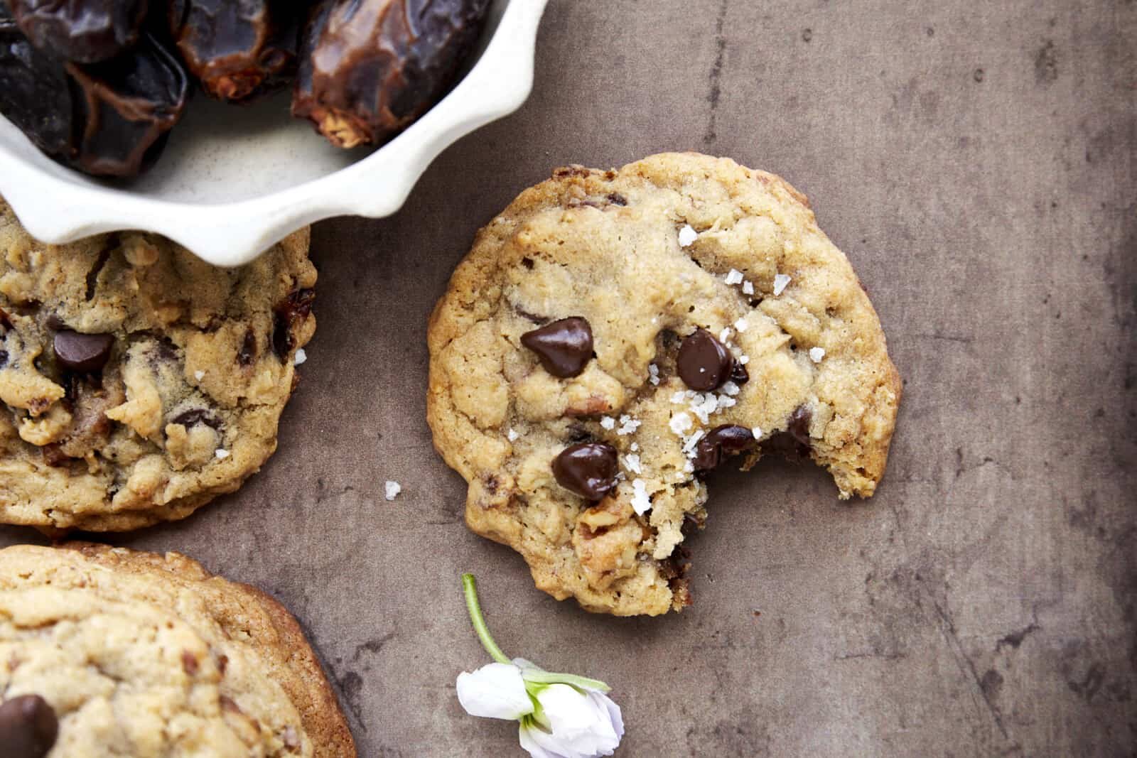 A date cookie topped with sea salt with a bite missing.