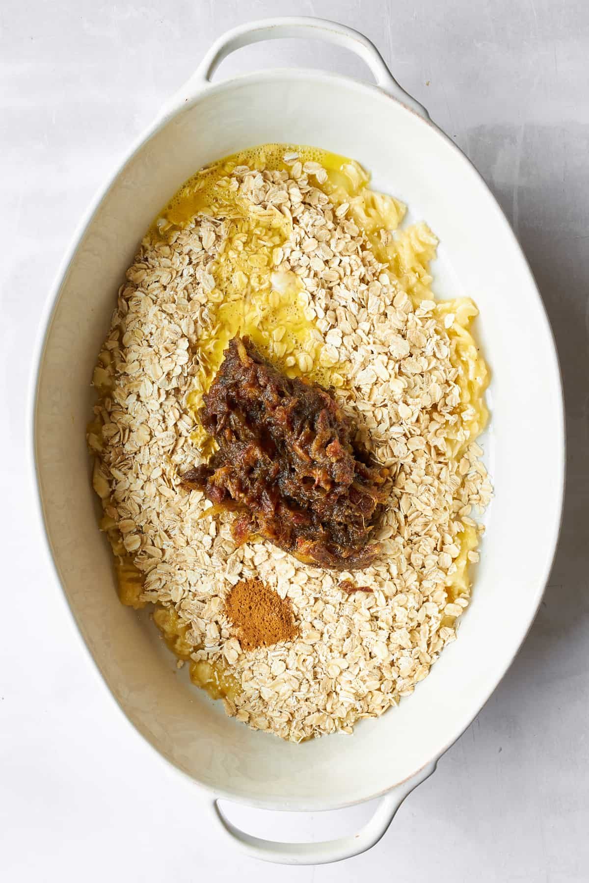 Ingredients for banana date oatmeal in an oval baking dish.