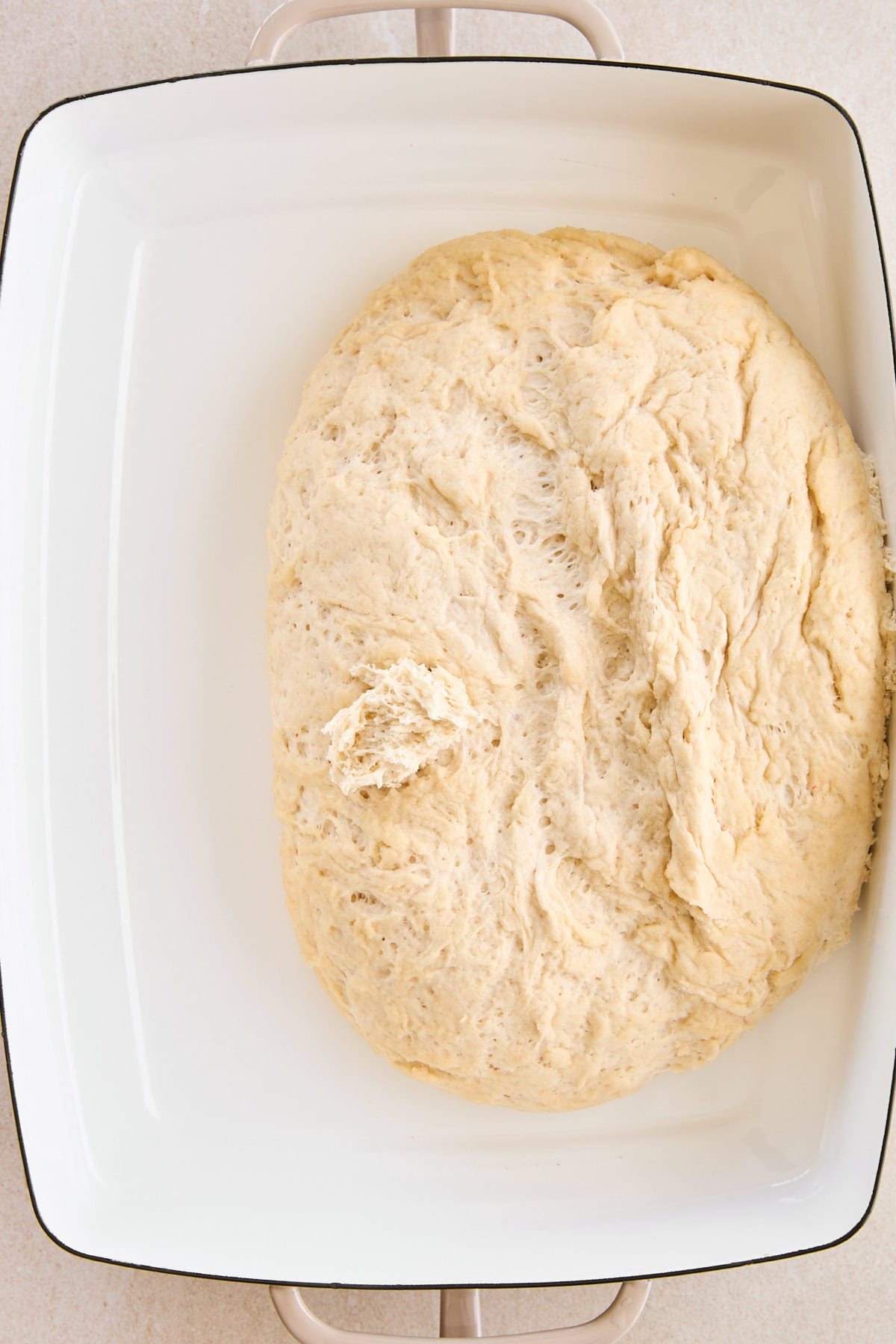 Focaccia dough in a baking dish.