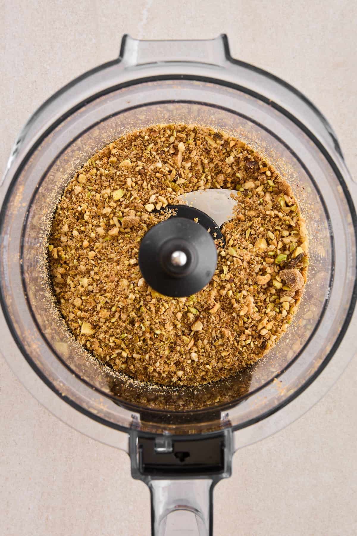 A sweet nut mixture in the bowl of a food processor.