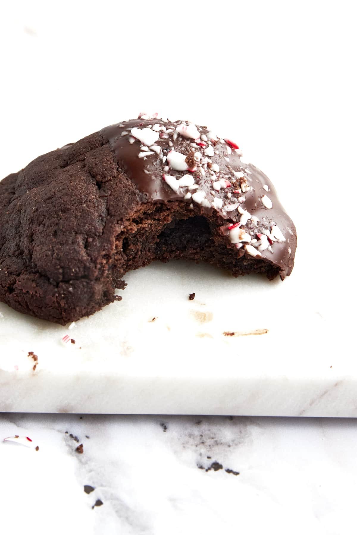 A dark chocolate dipped chocolate peppermint cookie topped with candy cane pieces.
