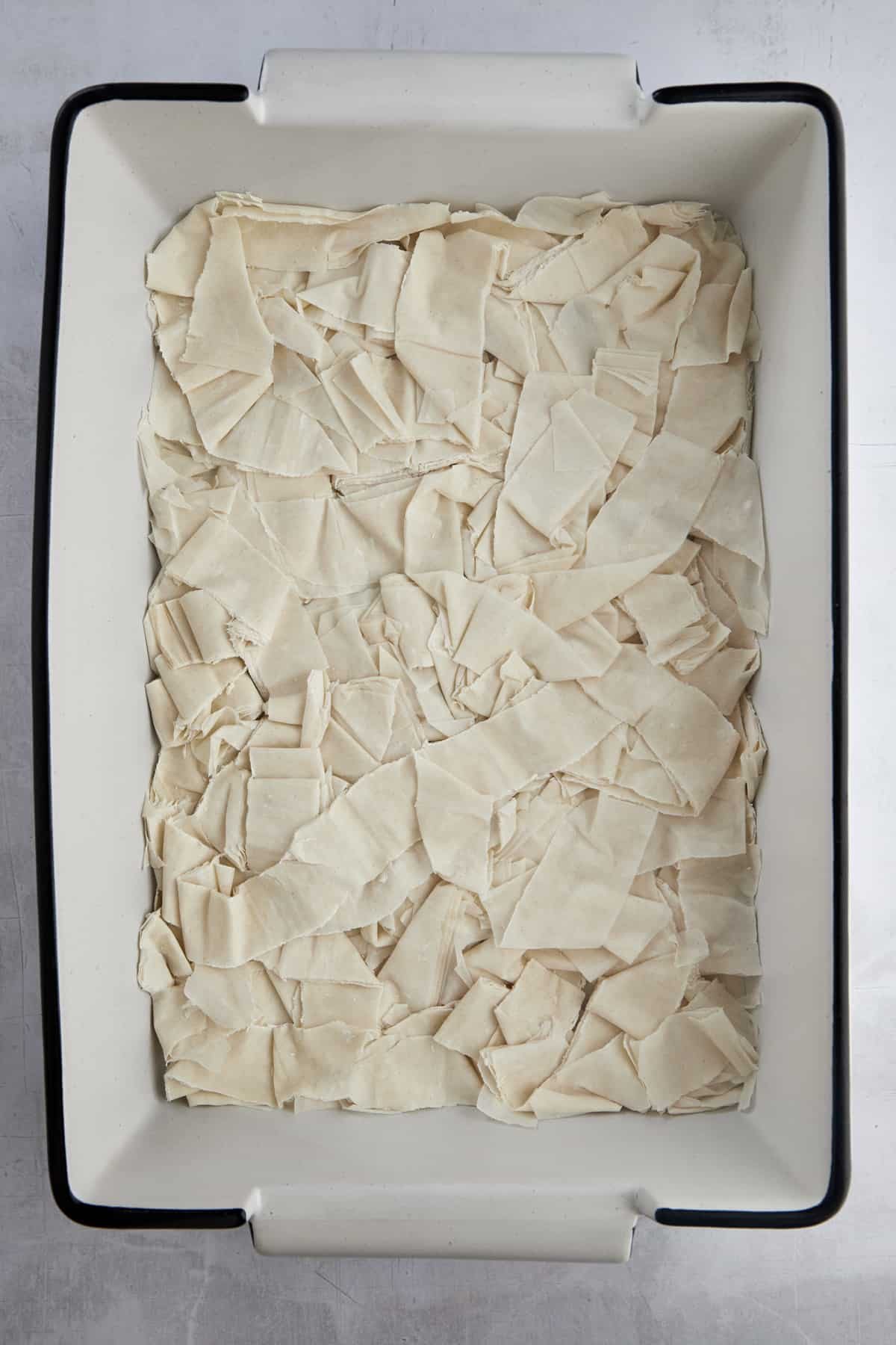 Phyllo dough pieces layered in a baking sheet.