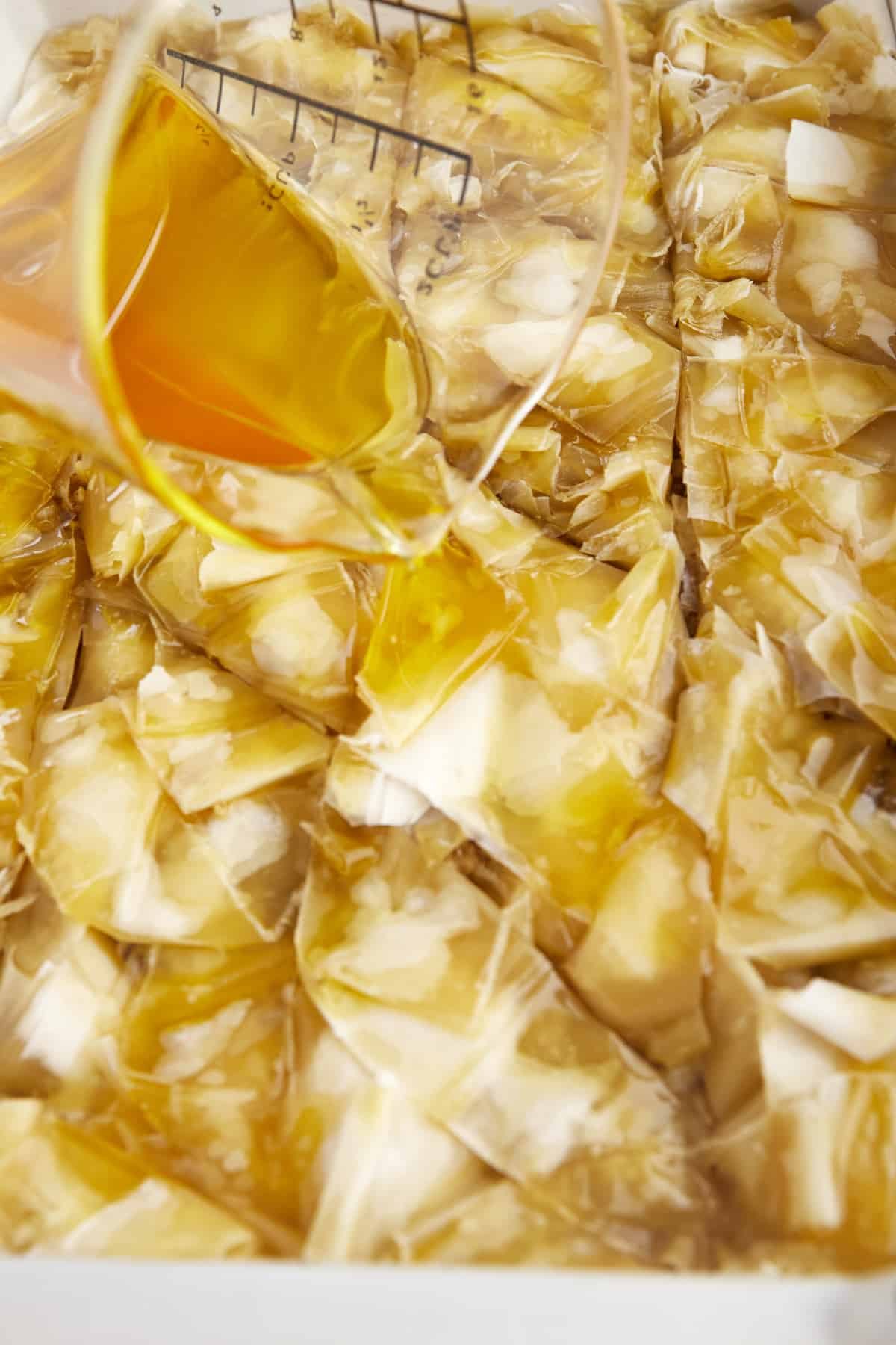 Simple syrup being poured over an unbaked easy baklava recipe.