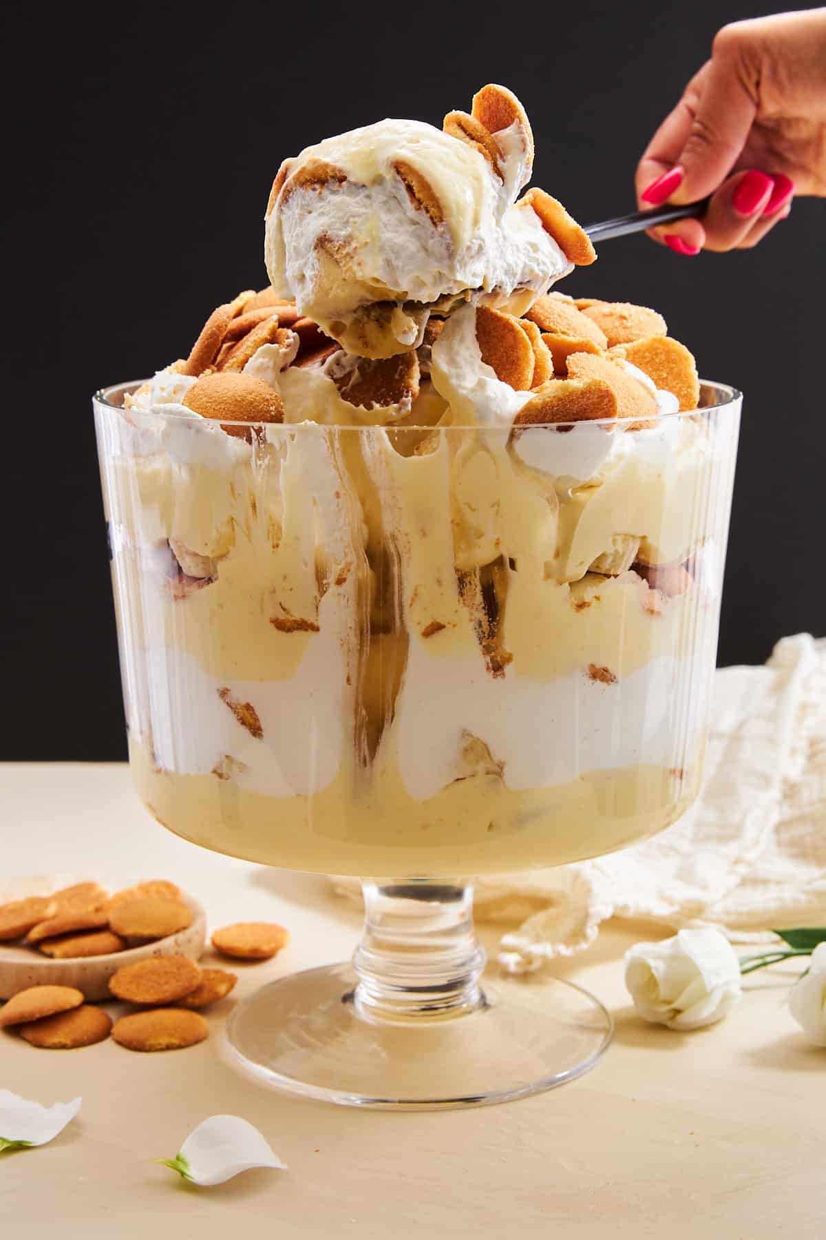 A spoon lifting a scoop of easy banana pudding from a trifle bowl.