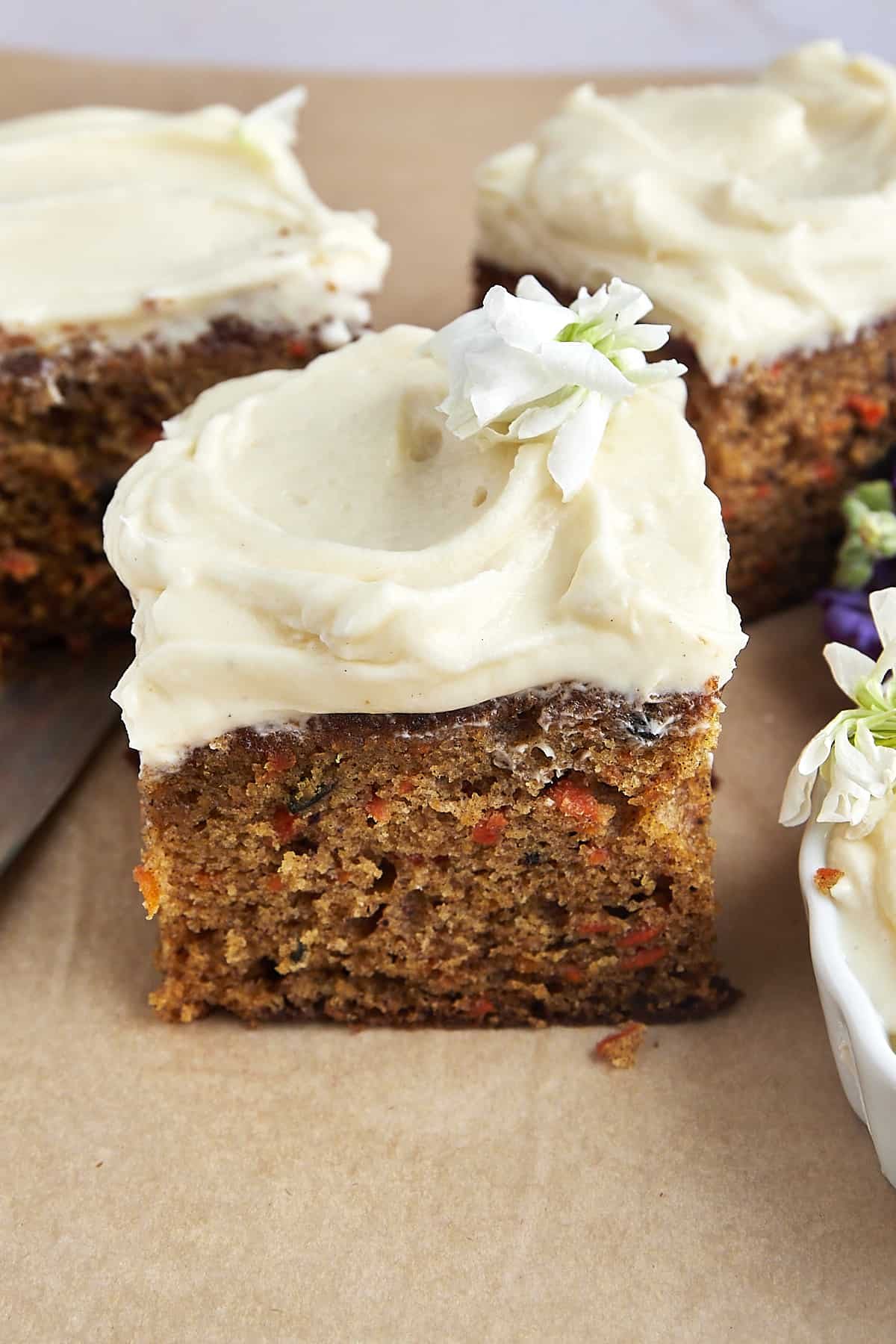 A square piece of carrot cake topped with cream cheese frosting.