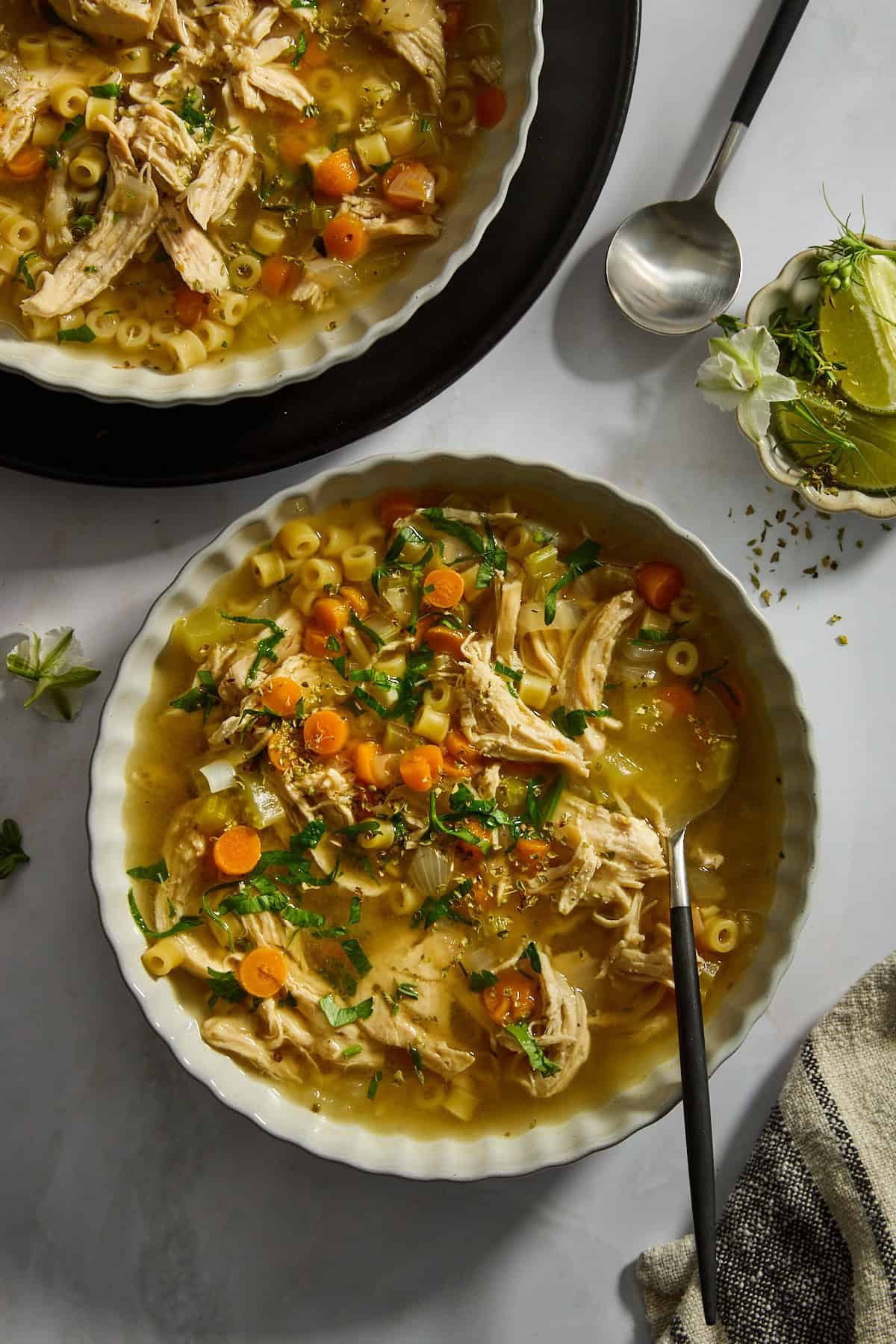 A bowl of from-scratch chicken noodle soup with a spoon sticking out.