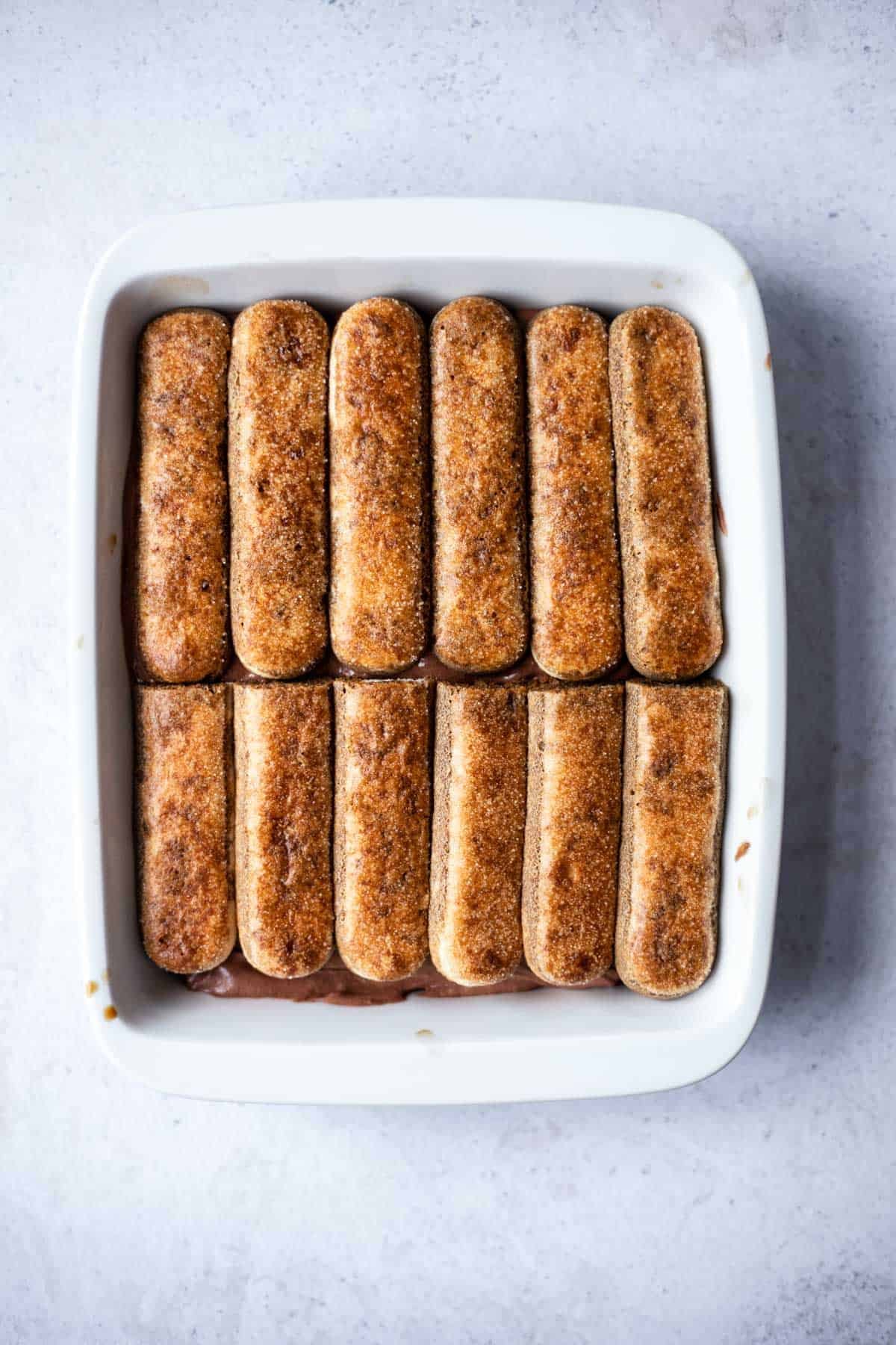 layers of ladyfingers and chocolate mascarpone in a baking dish.