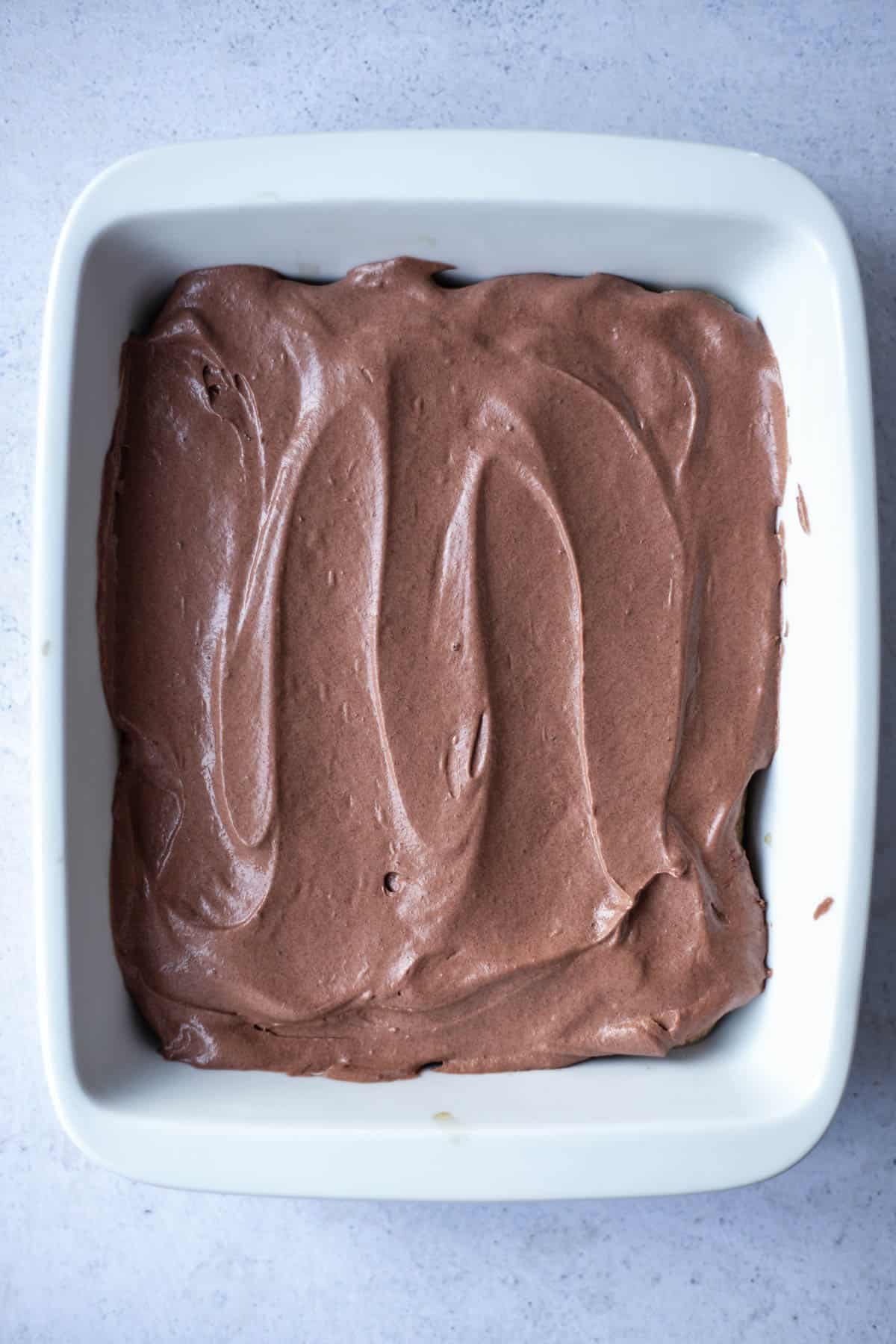 chocolate mascarpone spread over ladyfingers in a baking dish.