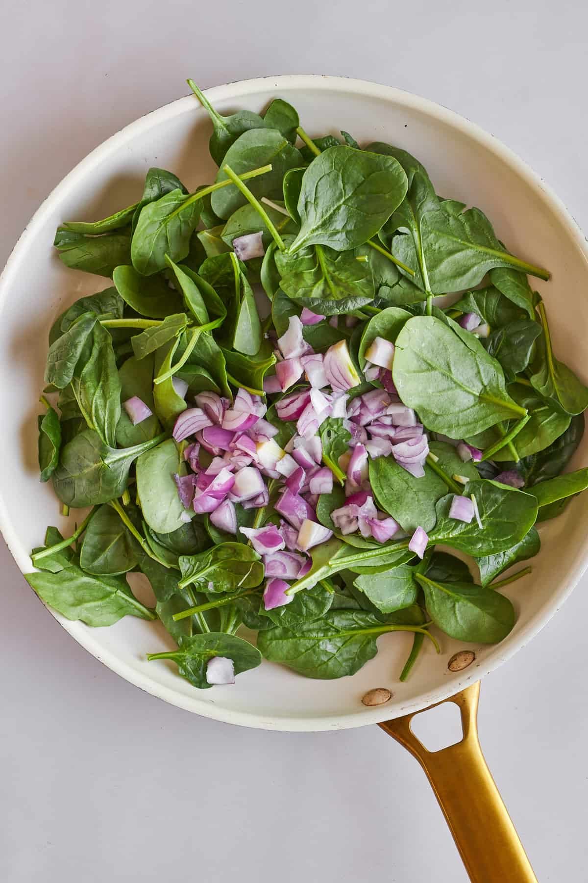 Spinach and shallot sautéeing in a skillet.