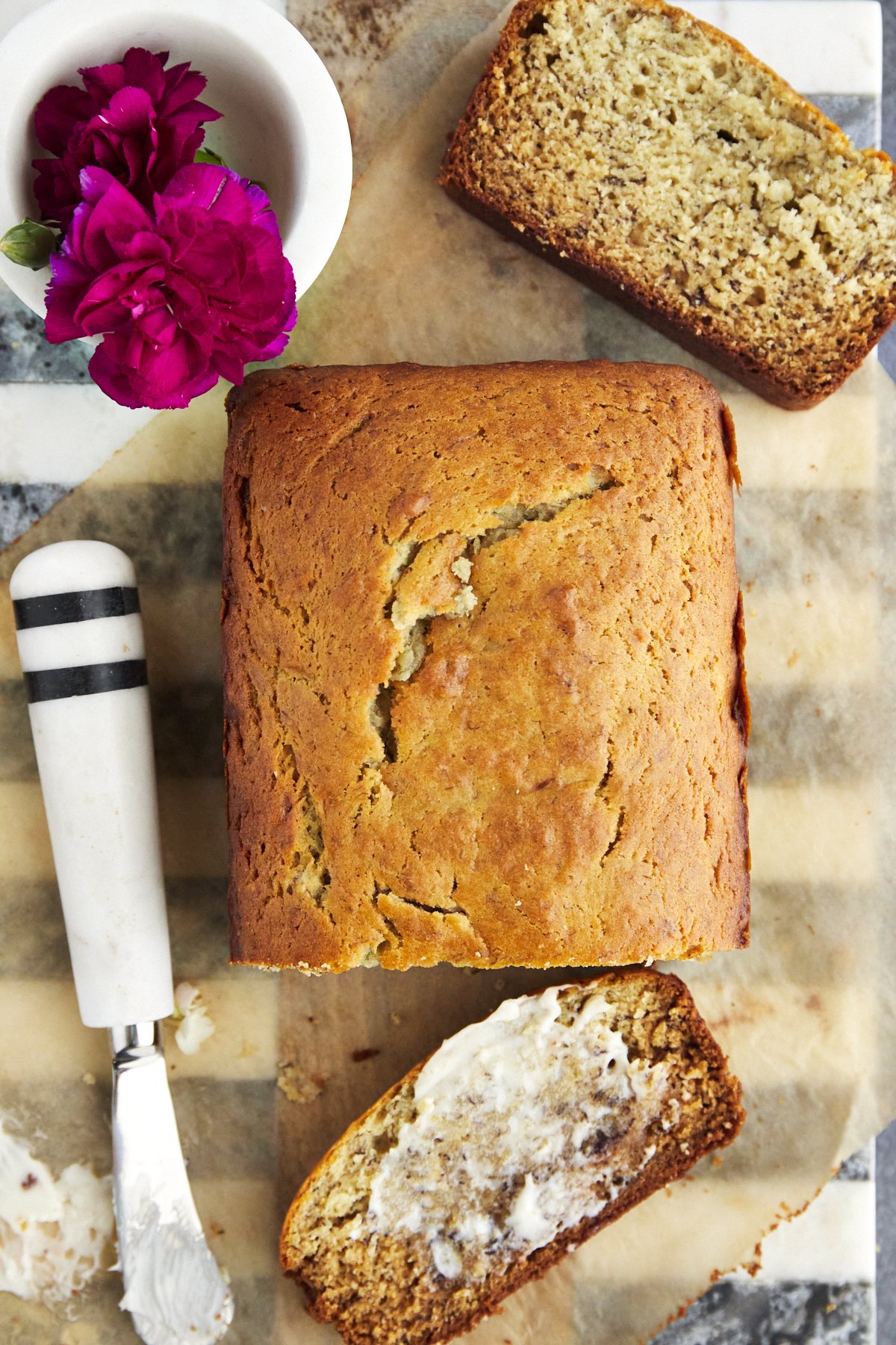a loaf of one bowl banana bread with a slice cut and butter smeared on top