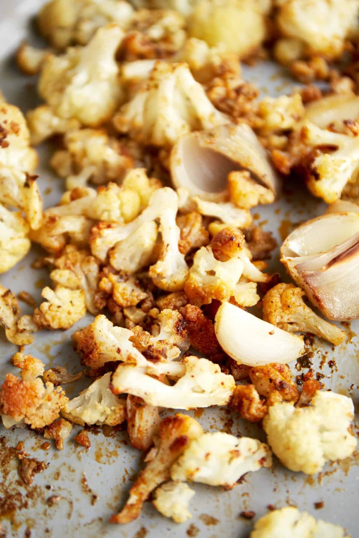 Roasted cauliflower, shallots, and onions on a baking sheet.